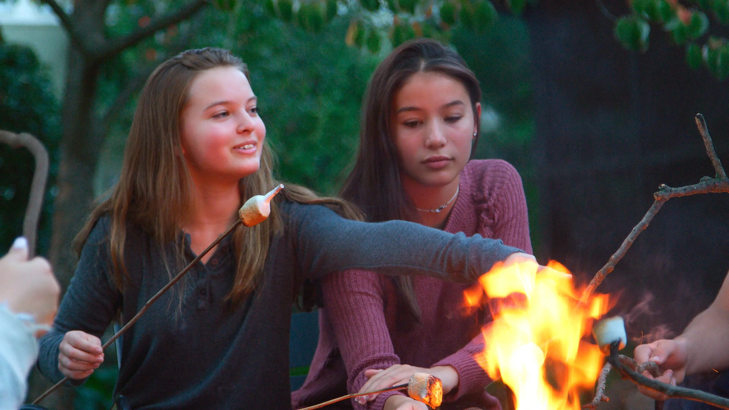 teenage girls roasting marshmallows at camp