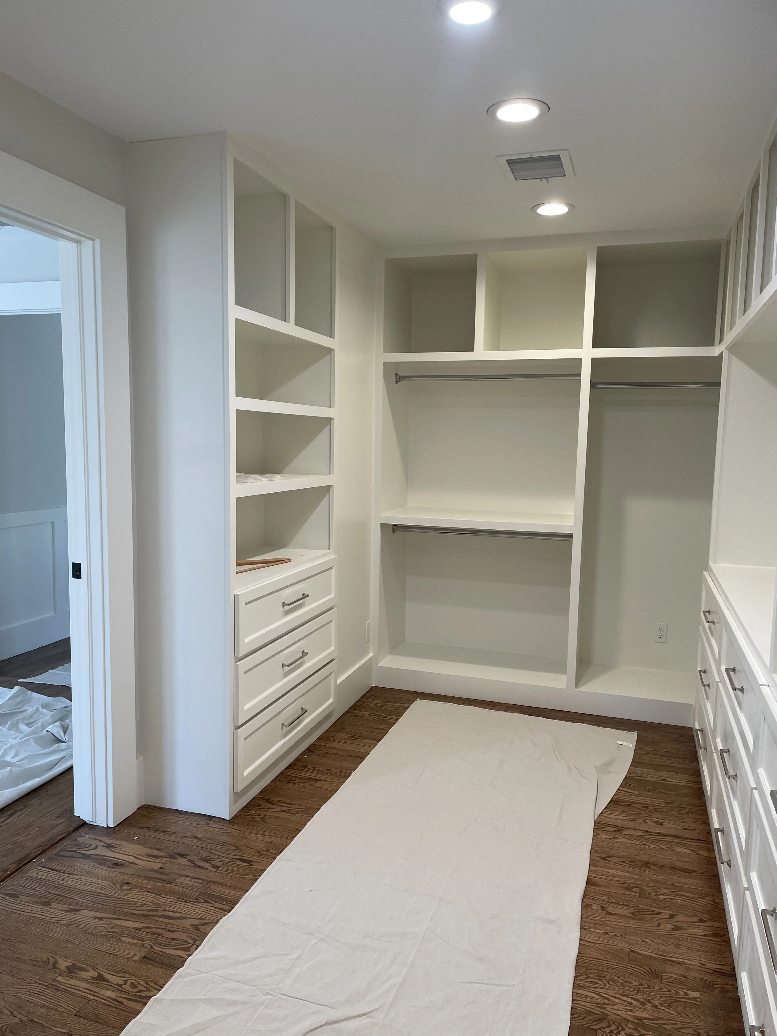 Bedroom walk in closet with shelves, hanging rods, and drawers.