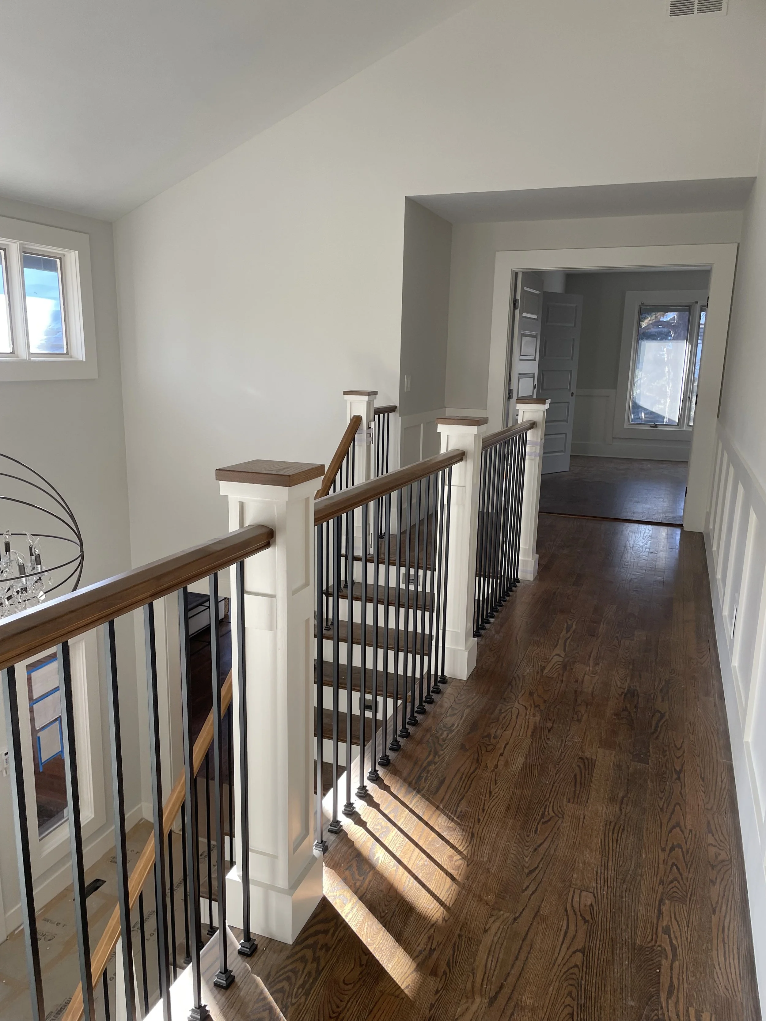 Wooden staircase rail with stain grade railing material and painted newel posts.
