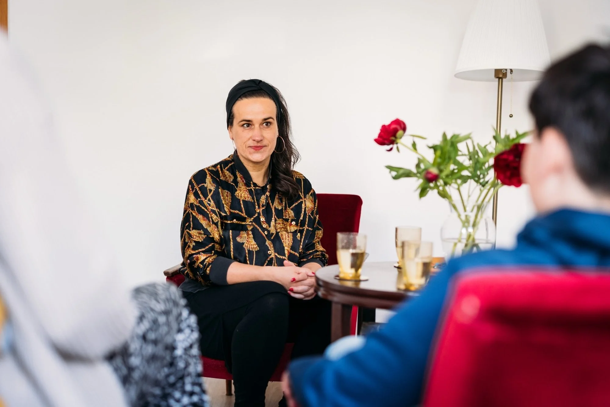 Therapiegespräch in kleinem Kreis mit Julia Pfeifer, Blumen im Hintergrund.