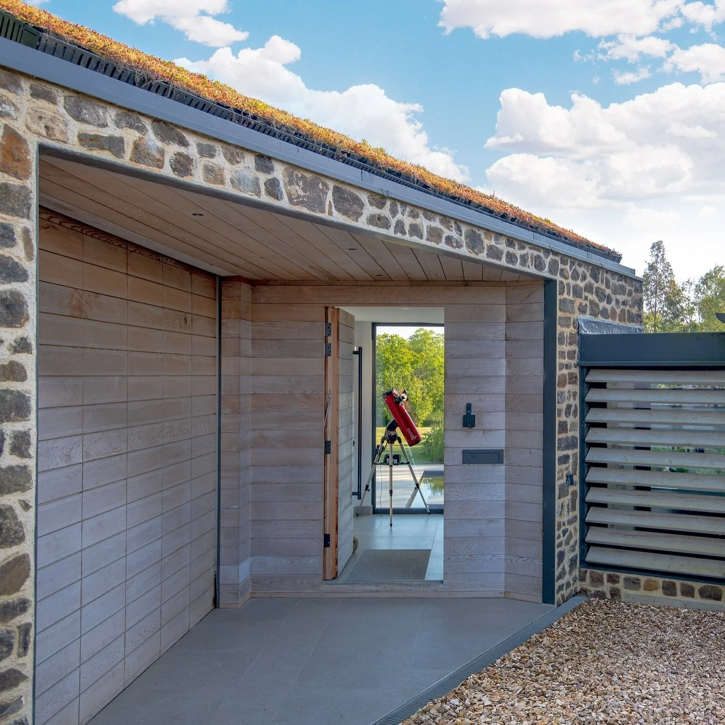 A seamlessly integrated garage and front door sharing the same canopy. 

The cedar wood and ironstone facade, coupled with the enticing view through the lobby, over the patio and into the landscape beyond, creates a warm and inviting entryway.

This 