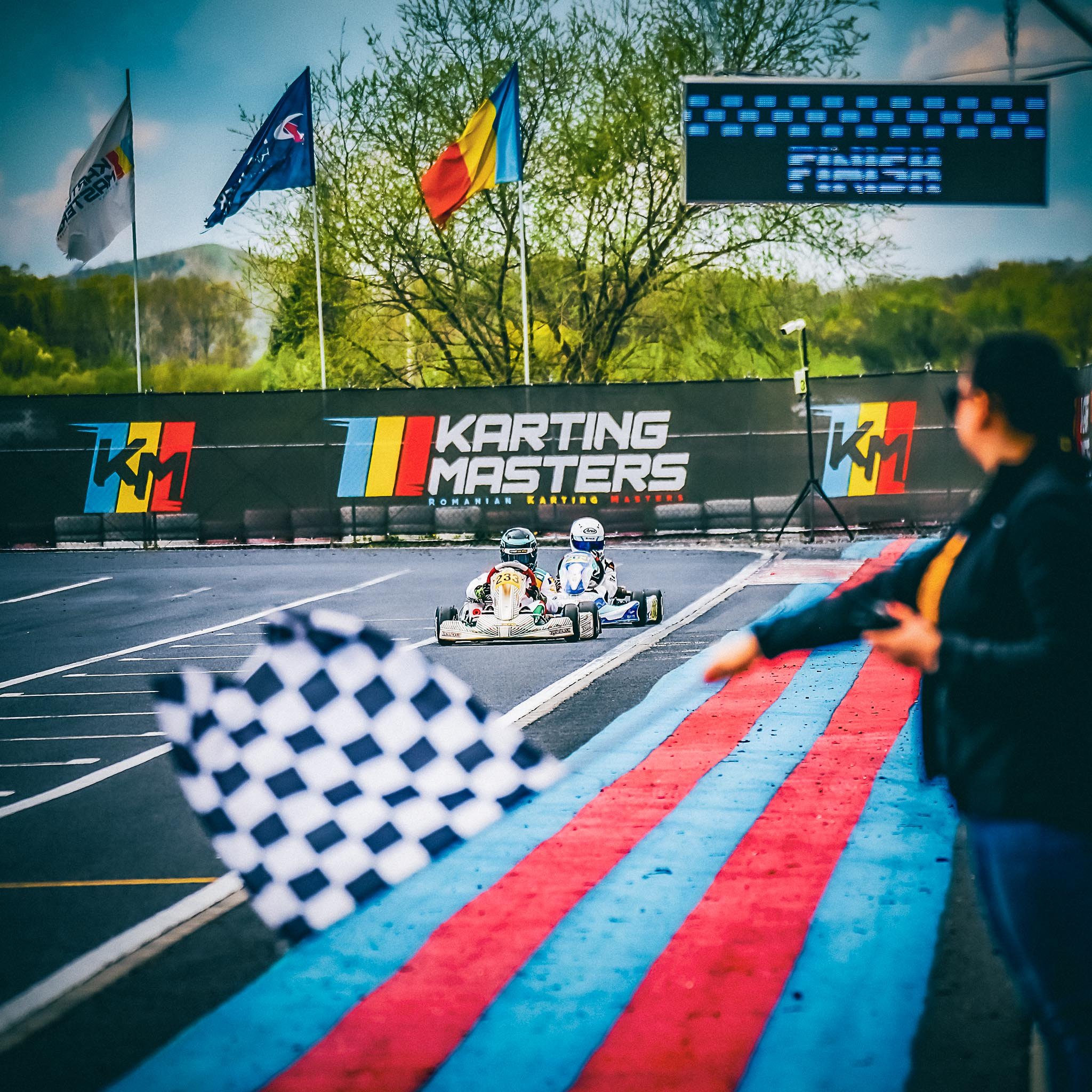 David Nicolaie, kart #33, trece linia de sosire în luptă strânsă pentru victorie la o etapă din Karting Masters, sub steagul în carouri și privirea arbitrilor.