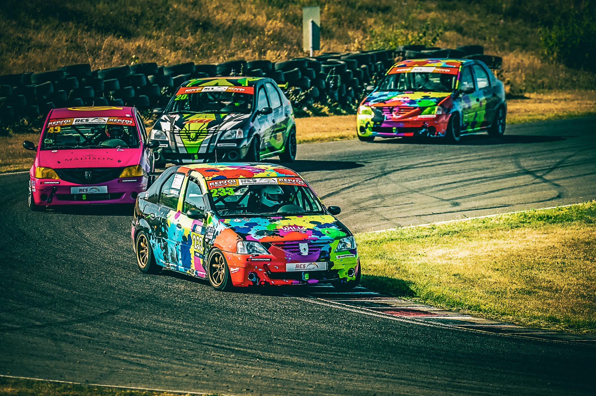 David Nicolaie pilotând mașina #233 într-o etapă Logan Cup din Romanian Endurance Series, pe un viraj de circuit, în fața plutonului de mașini