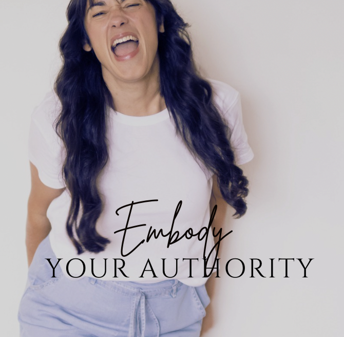 A woman with long dark blue hair laughing or shouting, wearing a white t-shirt and light-colored pants, with the text "Empody Your Authority" overlaid on the image.