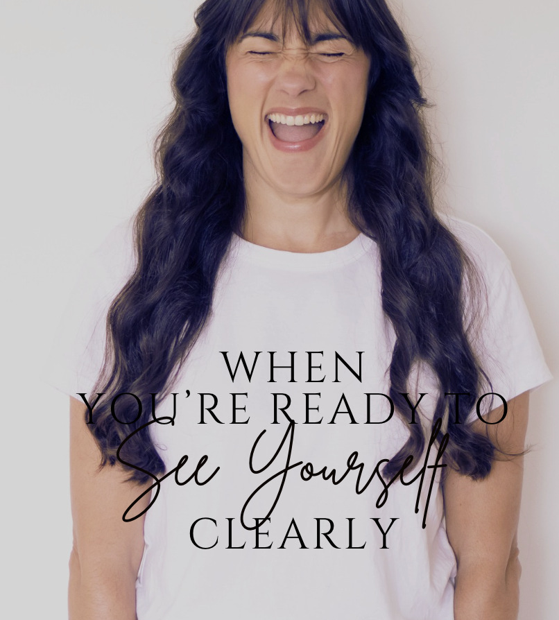 A woman with long dark hair working on a laptop with Google Classroom open, sitting at a wooden table with two books on the right.