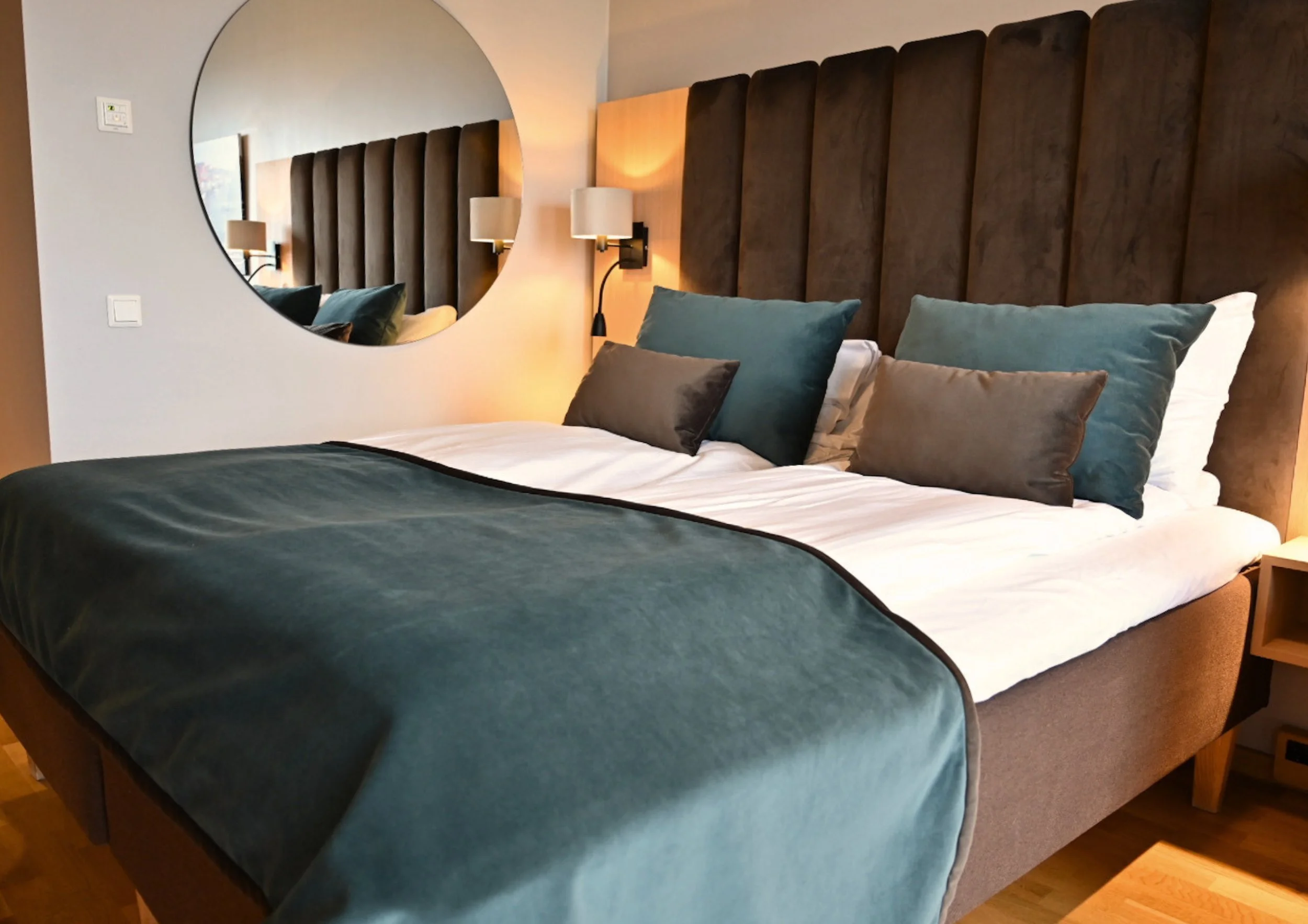 Dobbeltseng med speil på veggen på hotellrom