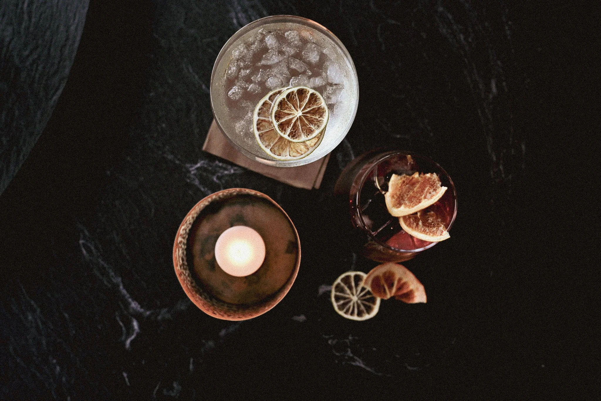 Et svart marmorbord med drinker og tørket lime og appelsin