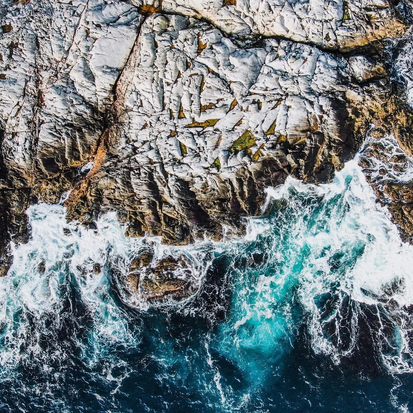 Dronefoto av bølger som bryter mot holmer.