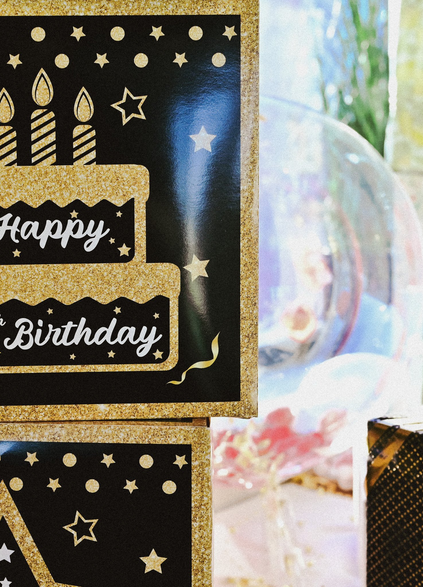 Bursdagskort med gullfarget glitter og bilder av kaker og stjerner. Tekst som sier "Happy Birthday".