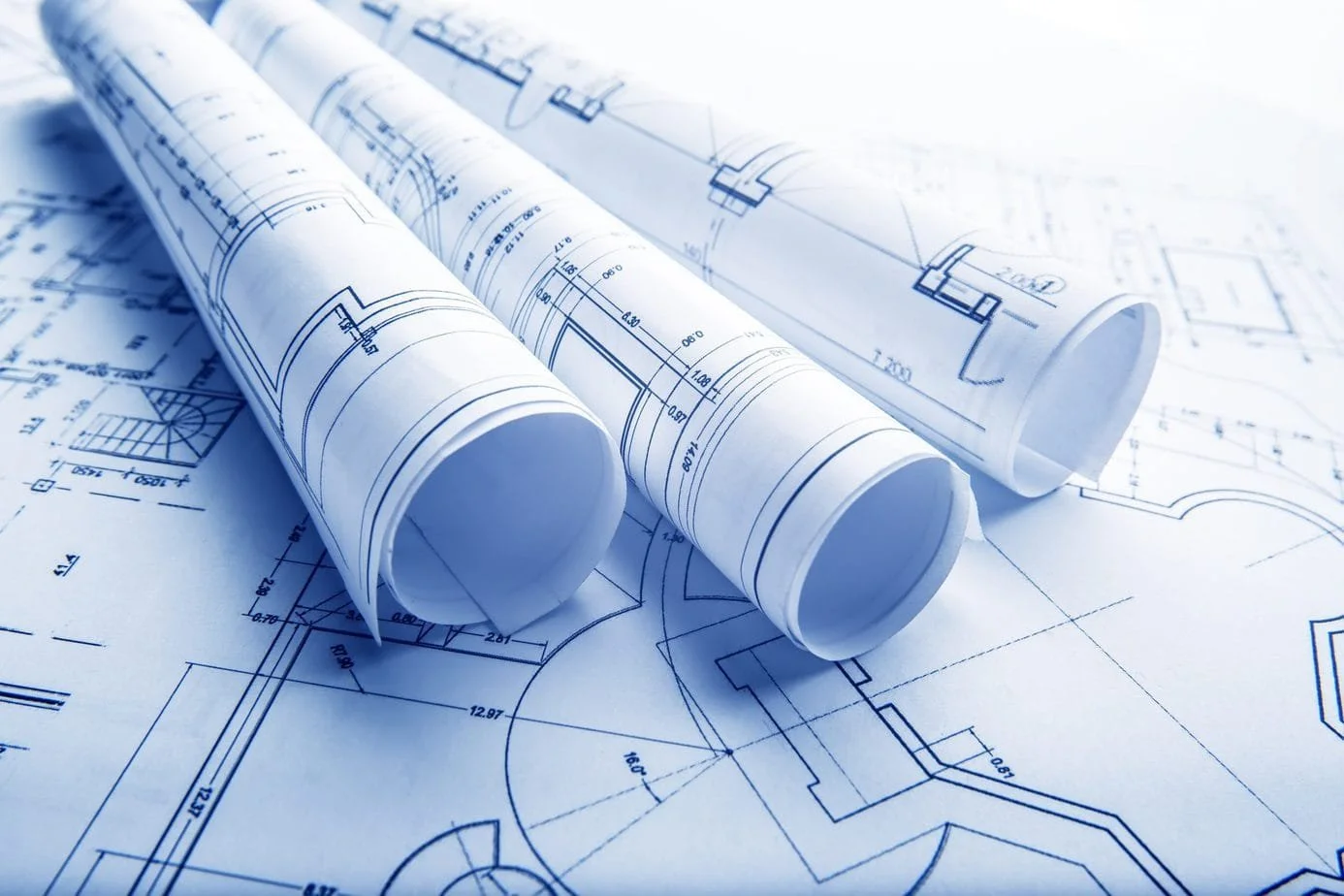 Rolled engineering blueprints on a table with architectural plans.
