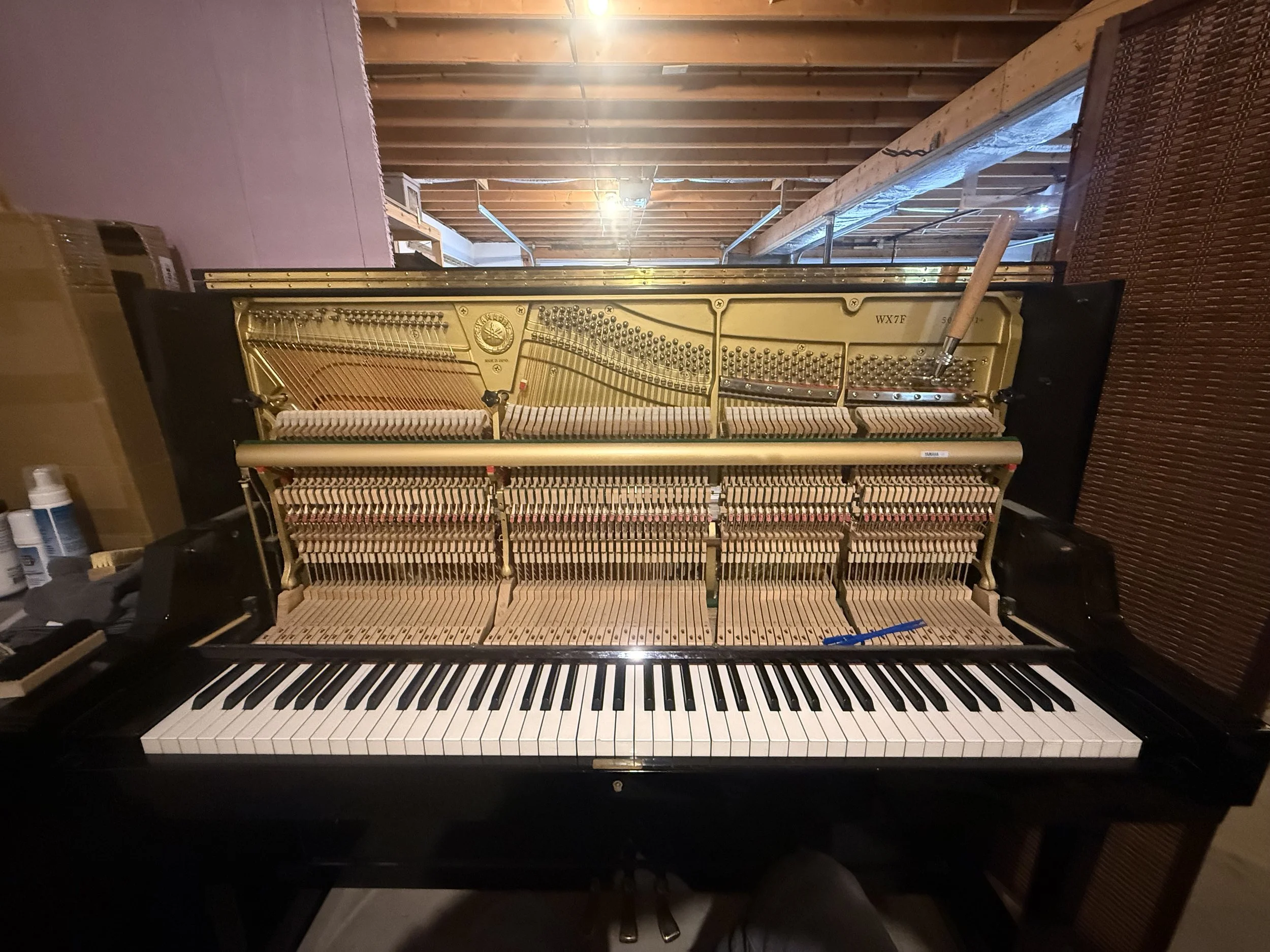 An upright piano with its top lid lifted open, revealing internal strings and mechanisms.