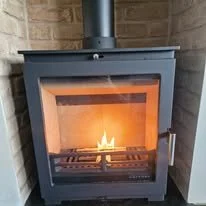 Brick slip tiled fireplace with locally sourced granite hearth from Landford Stone Romsey, designed to withstand heat from a log burner in a Hampshire home.