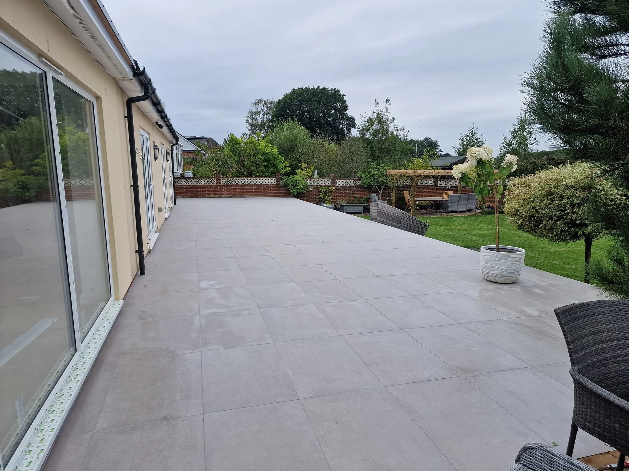 Large 20mm outdoor porcelain patio tiles installed over 100 square metres in a landscaped garden in Hedge End, Hampshire, creating a durable and stylish outdoor living space.