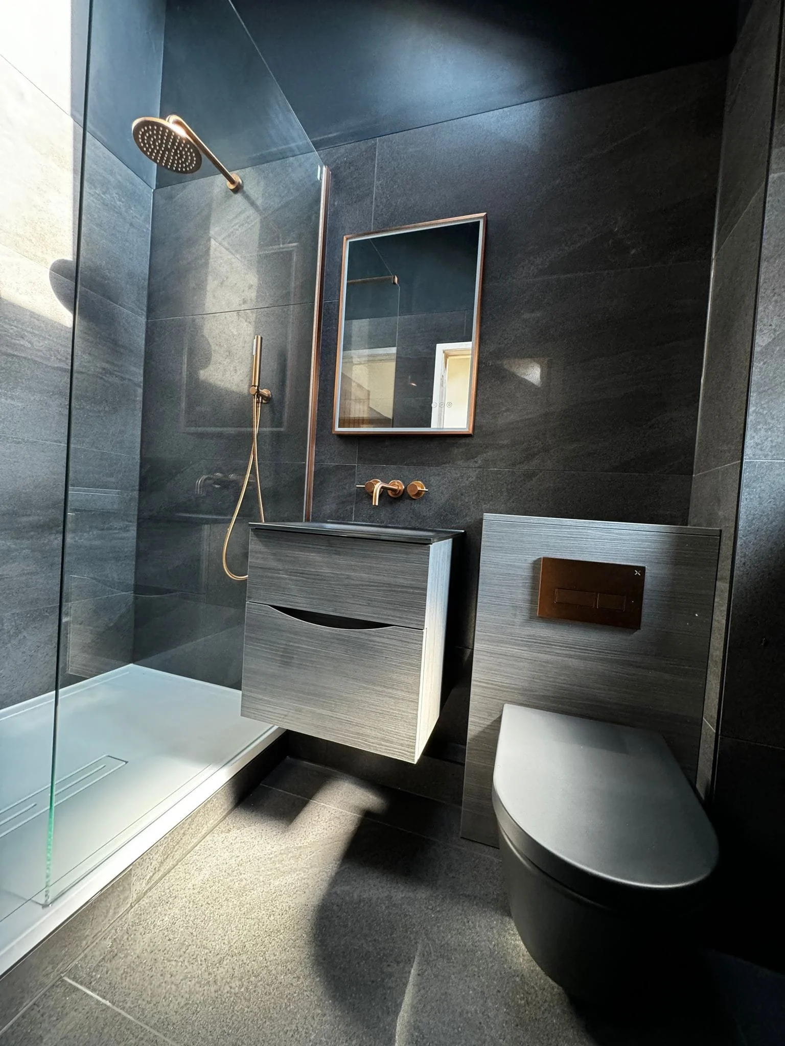 Modern black bathroom tiles installed with clean lines and a contemporary finish in a Hampshire home, creating a sleek and stylish bathroom space.