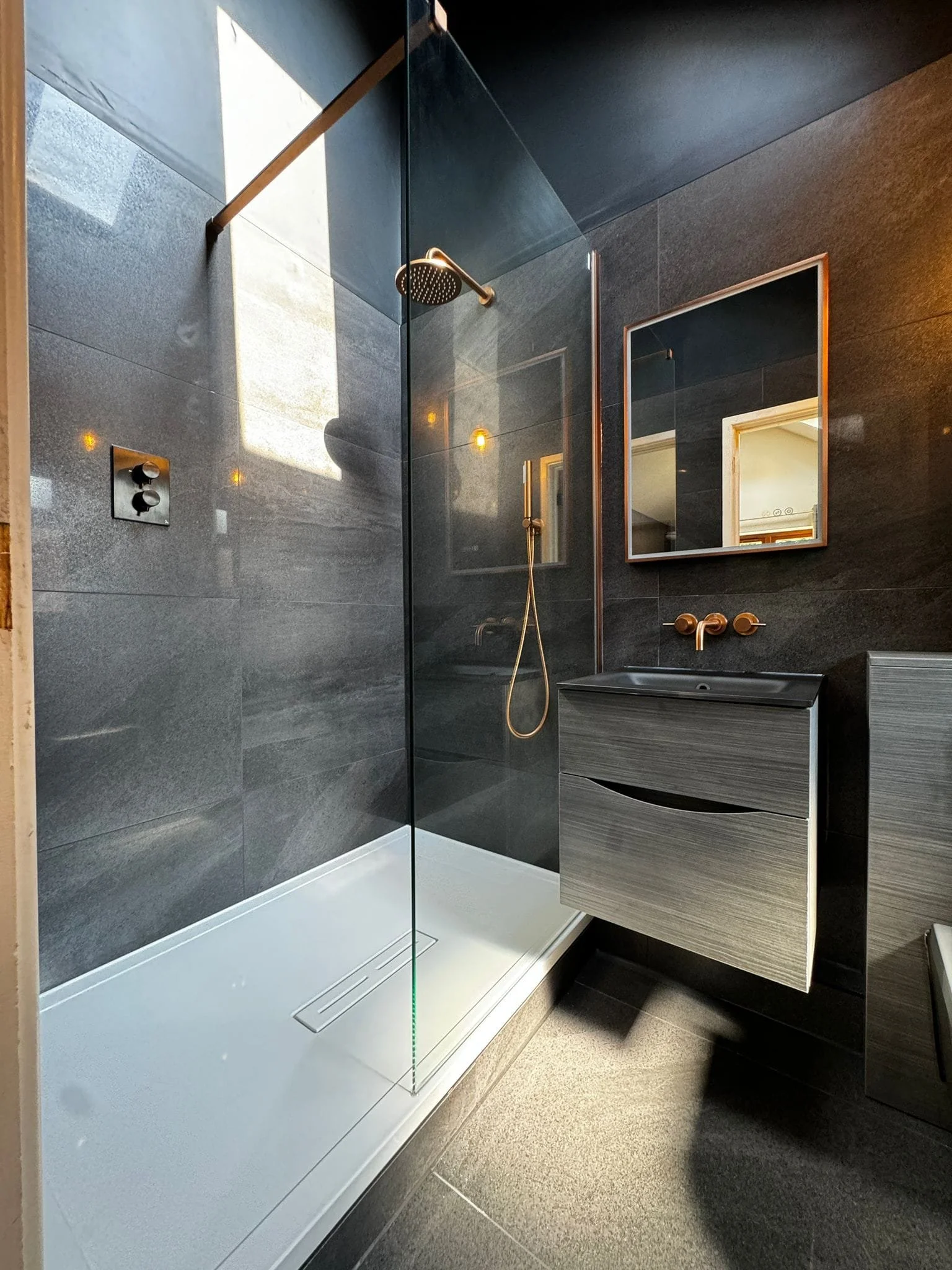 Modern black bathroom tiles installed with clean lines and a contemporary finish in a Hampshire home, creating a sleek and stylish bathroom space.