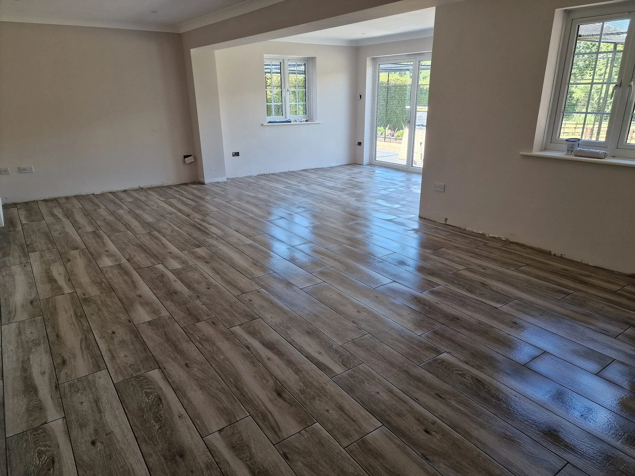 Seamless wood-effect porcelain tiles installed across multiple living spaces for a clean, modern flow.