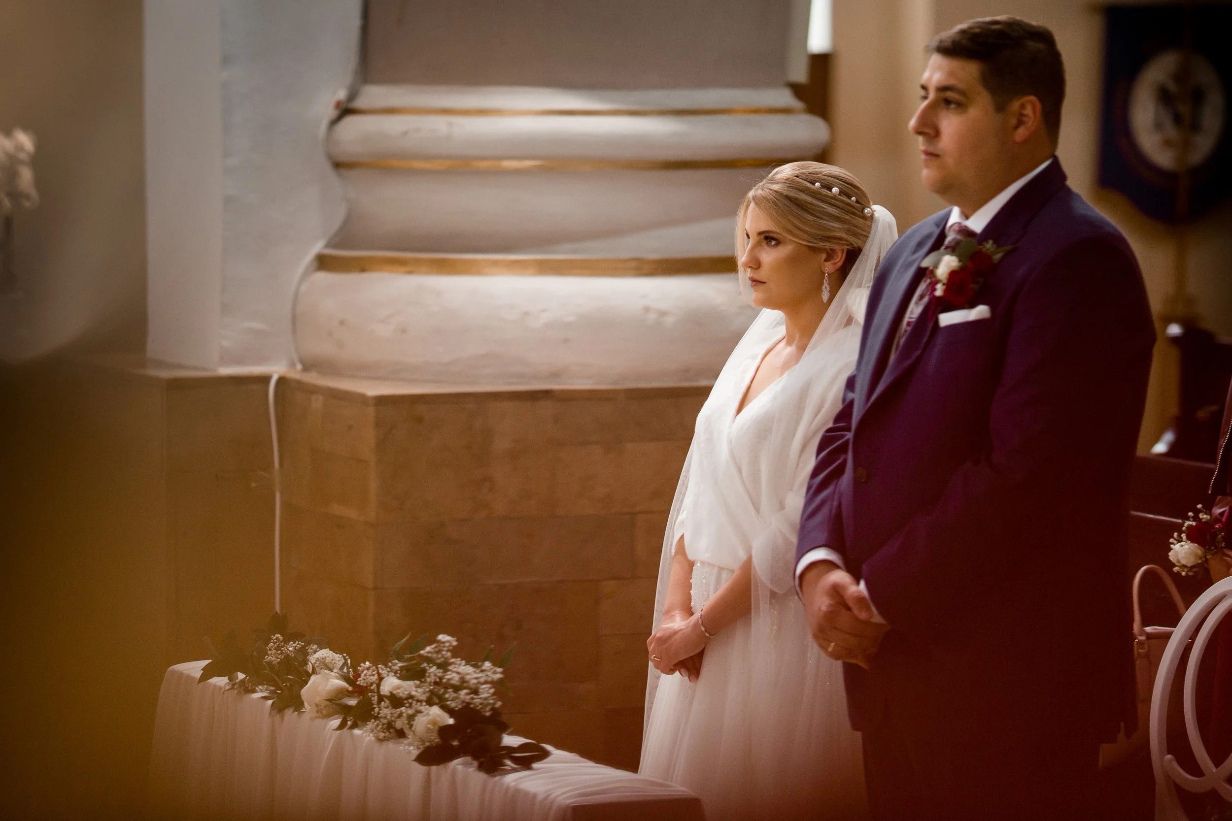 Bride and groom standing at altar during wedding ceremony inside church.