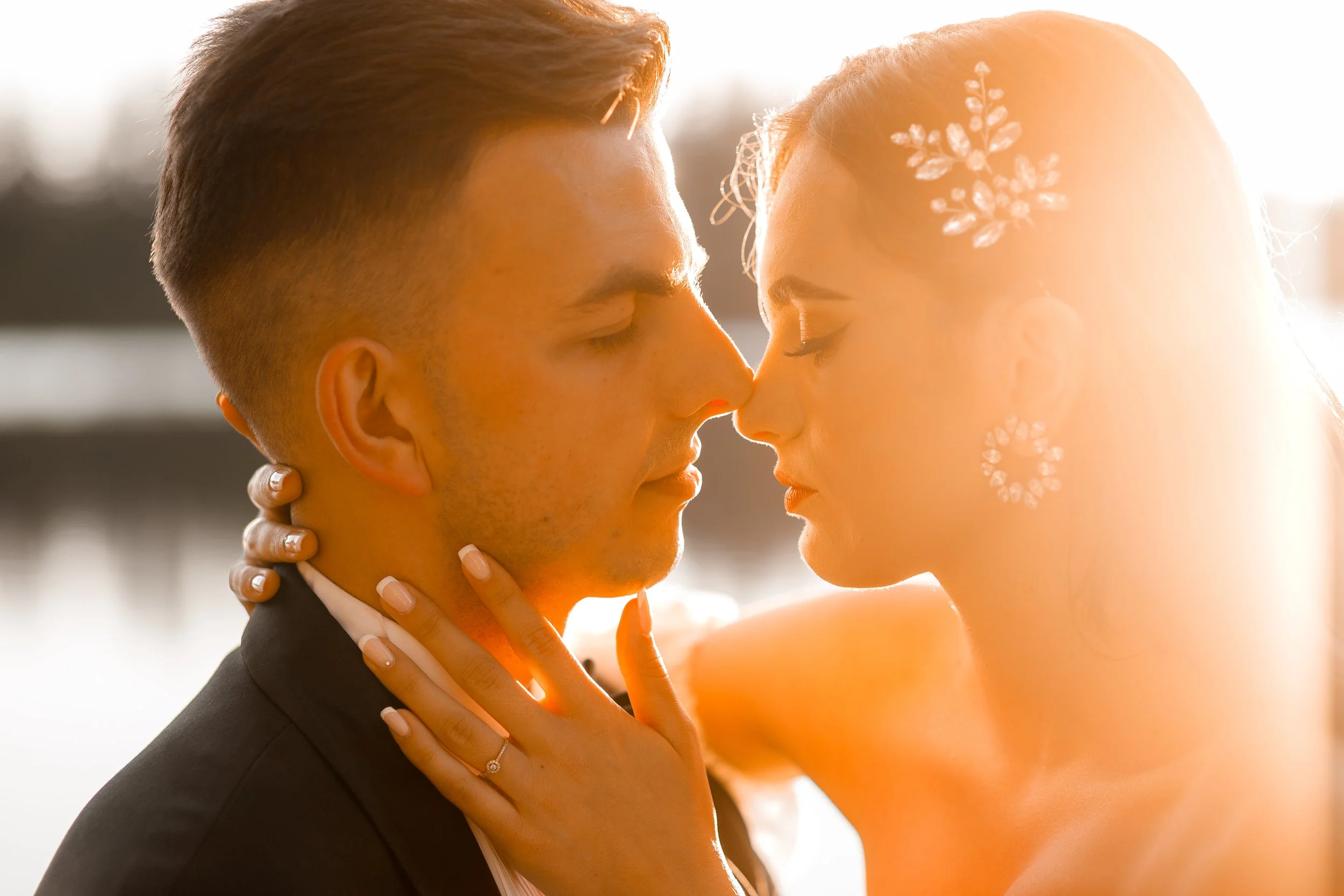 Romantyczne zbliżenie pary, której czoła stykają się z oczami zamkniętymi, podczas zachodu słońca.