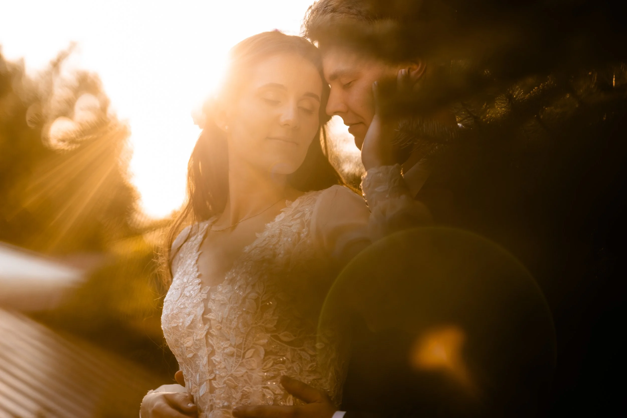 

Para młoda blisko siebie podczas zachodu słońca, oświetlona od tyłu przez słońce, co tworzy ciepłą poświatę.