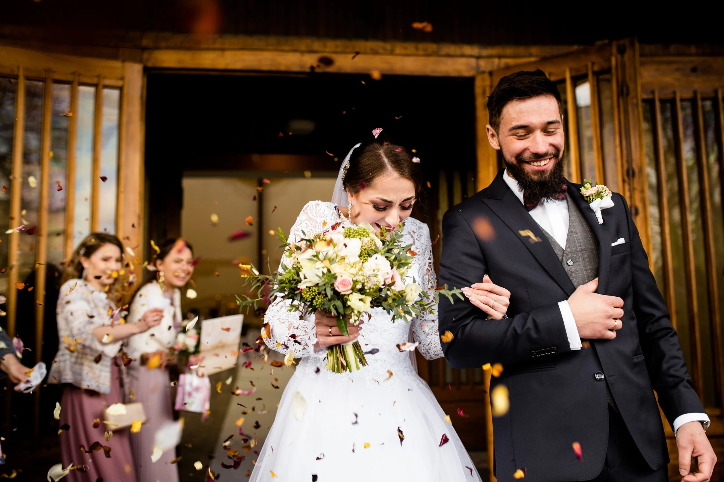 A bride and groom celebrating their wedding as confetti falls around them, with bridesmaids in the background.