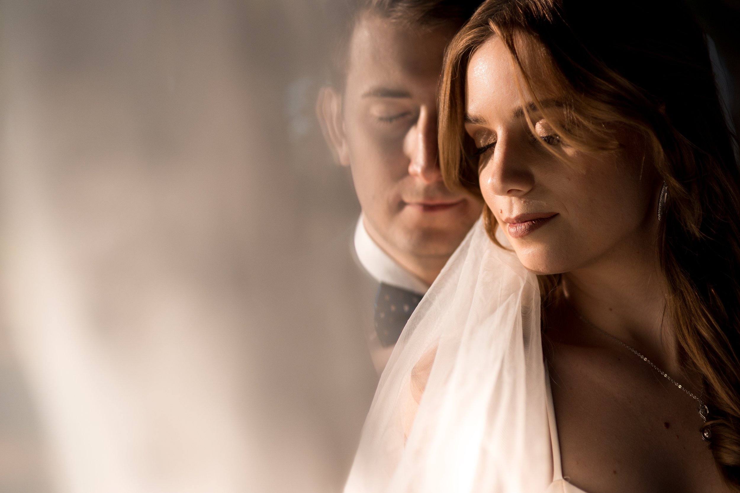 A close-up of a bride and groom with their eyes closed, sharing an intimate moment on their wedding day.