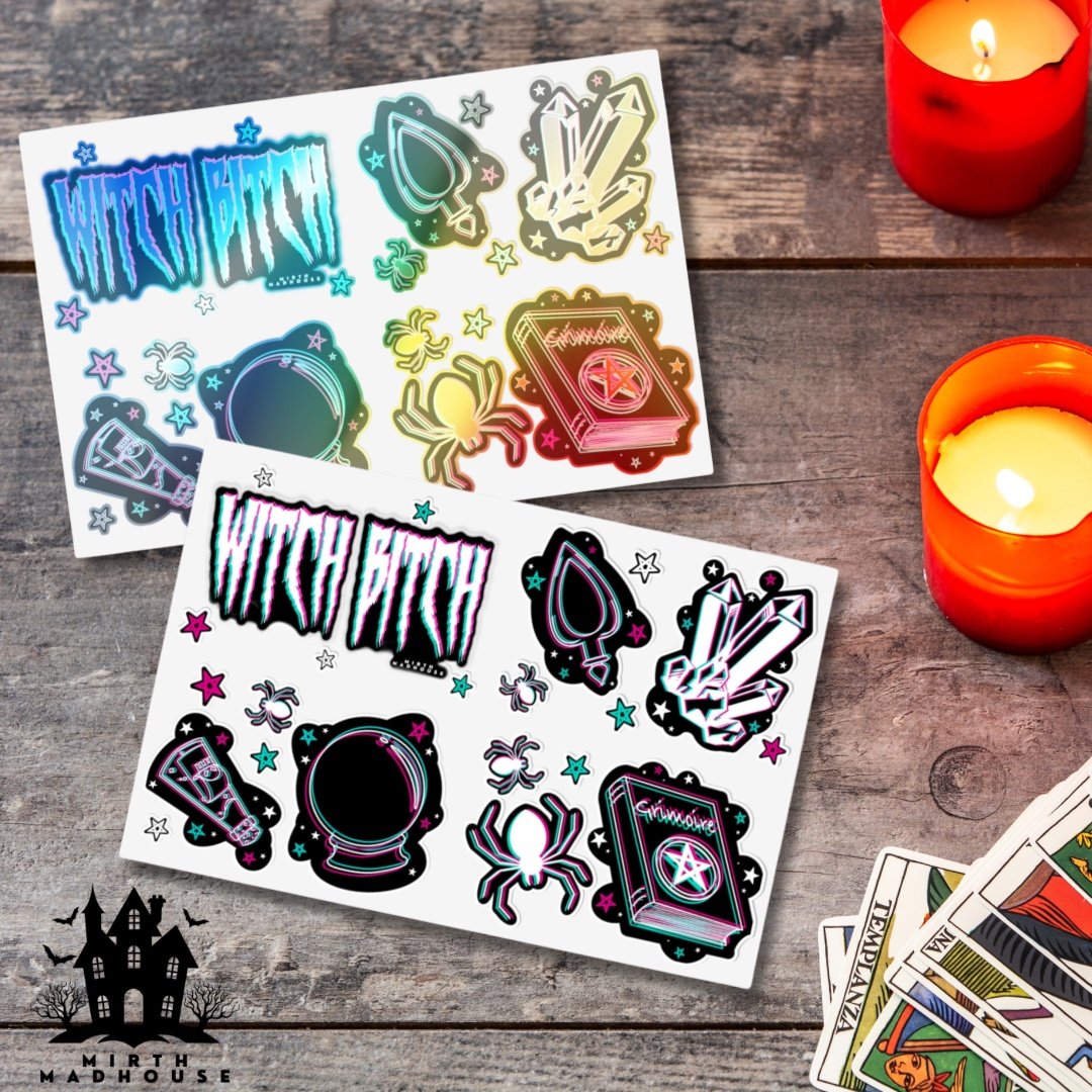 Sticker sheets with witch-themed designs, including crystal, spider, ouija planchette, and spellbook, on a wooden table with red candles and tarot cards.