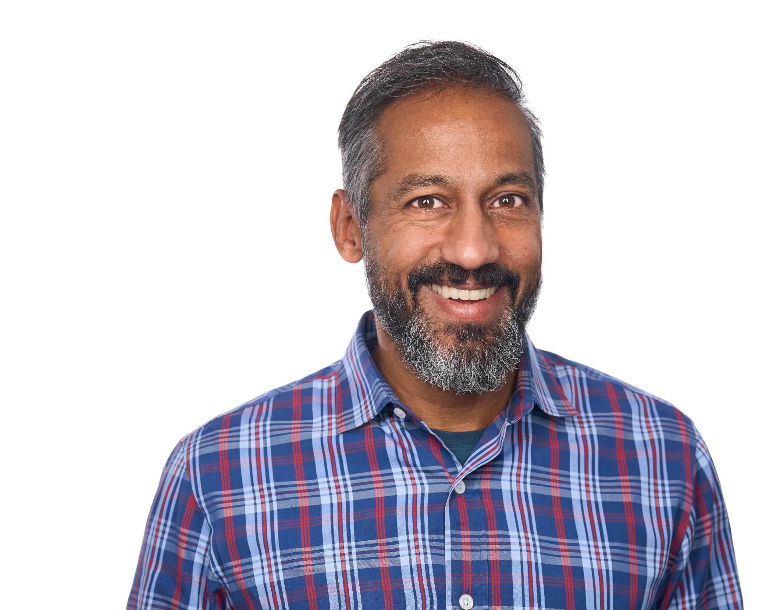 Smiling middle-aged man with a beard and short dark hair wearing a blue plaid shirt against a white background.