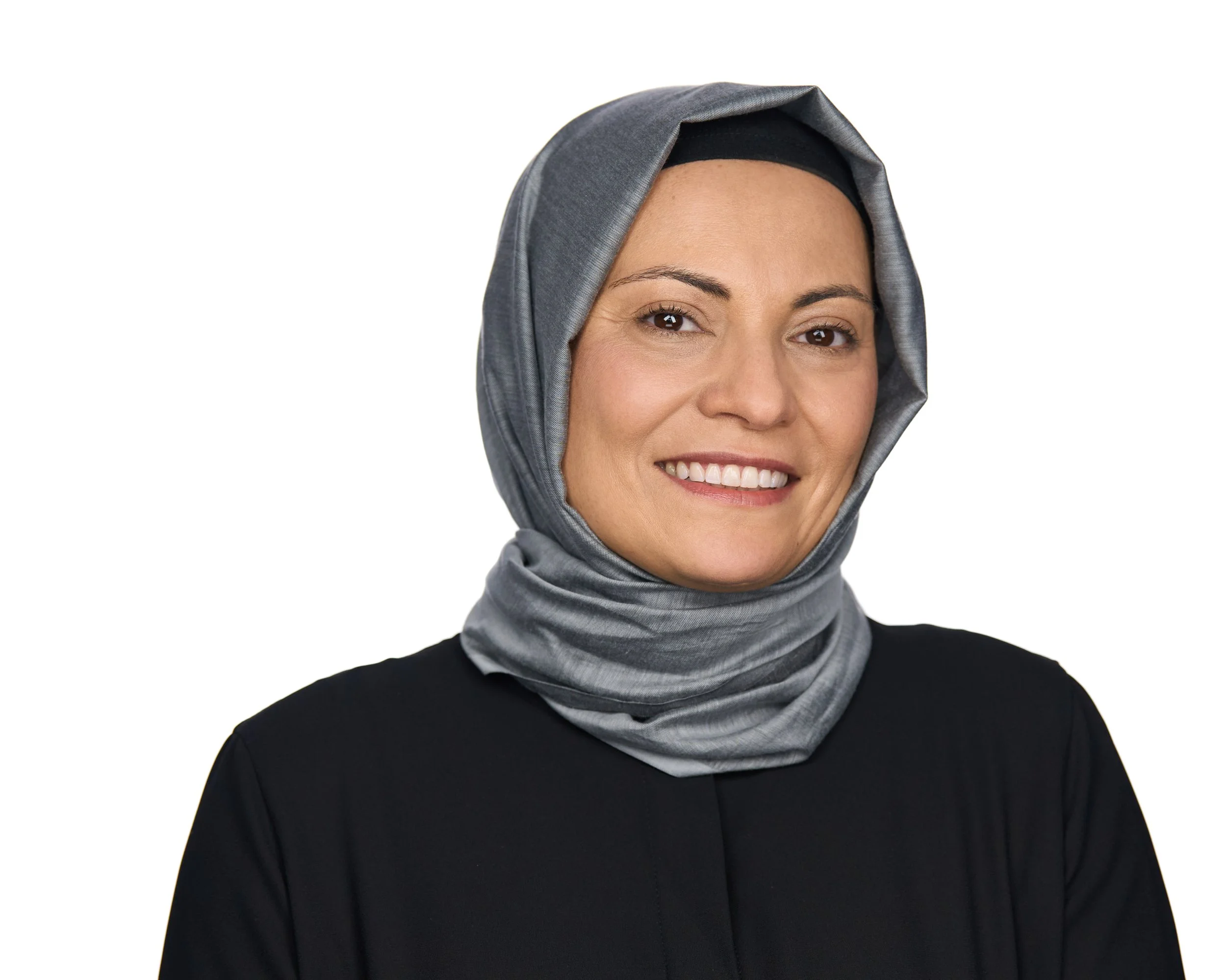Woman smiling, wearing a gray hijab and a black top.