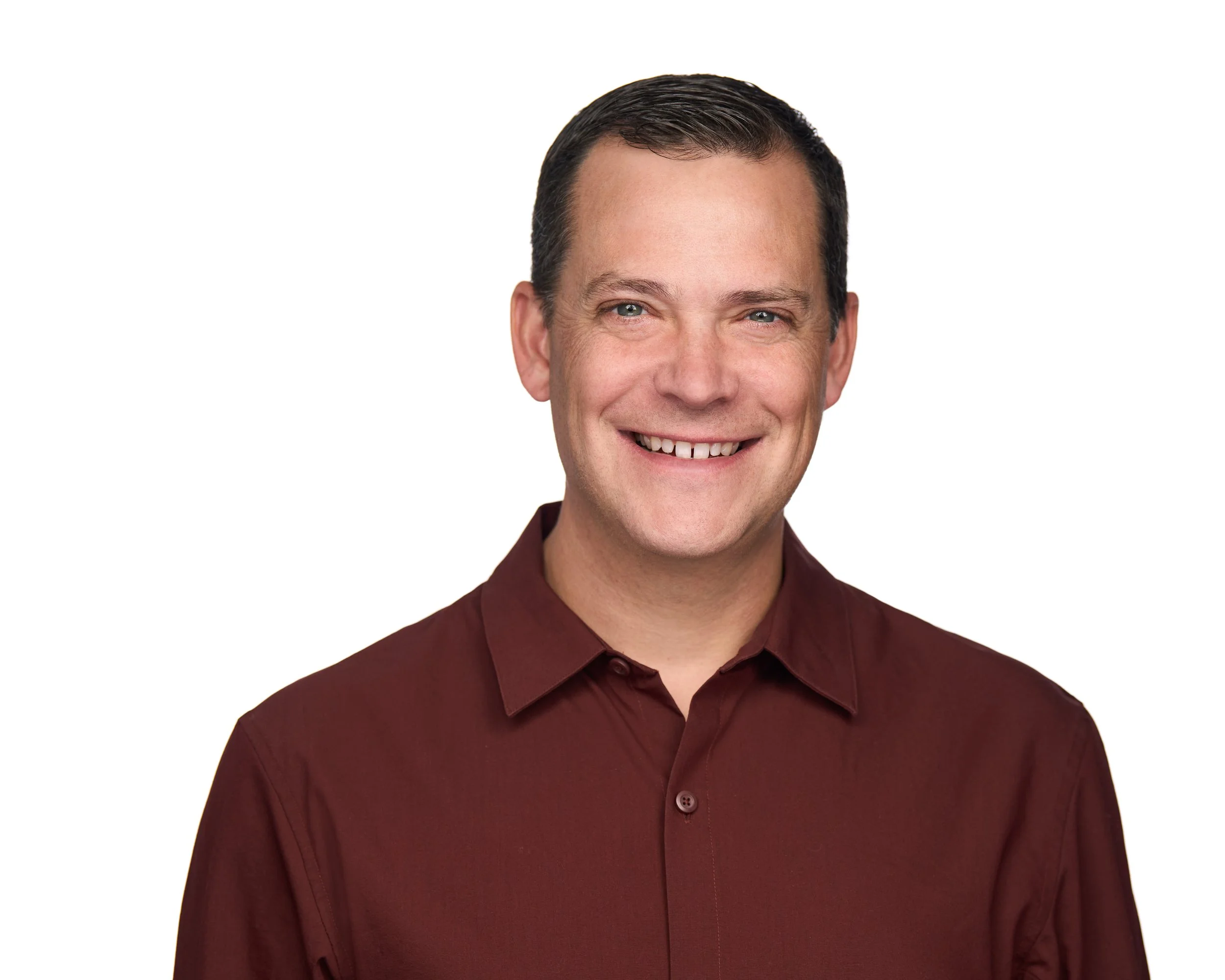 A smiling man with short dark hair, wearing a maroon button-up shirt, against a white background.