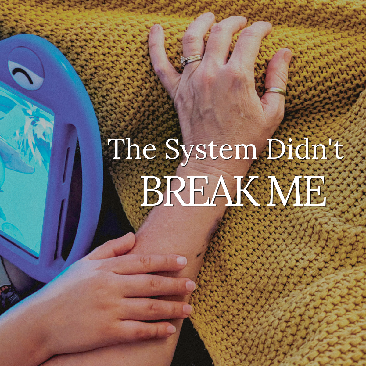 A child's hands resting on an adult's forearm on a yellow knitted blanket, tablet nearby. Text: "The System Didn't BREAK ME".