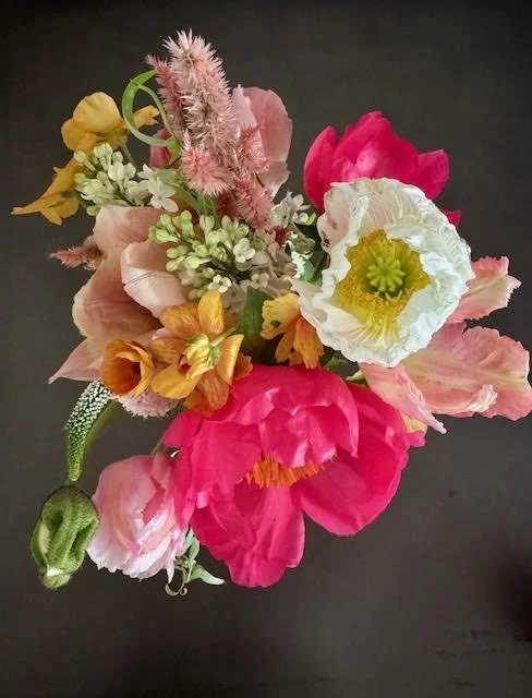 Bouquet of various colorful flowers including pink, yellow, white, and red blossoms against a dark background.