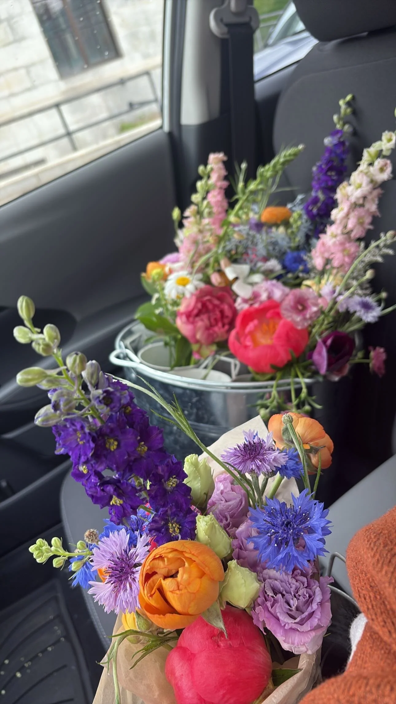 Two bouquets of colorful fresh flowers inside a car, placed on the seat.