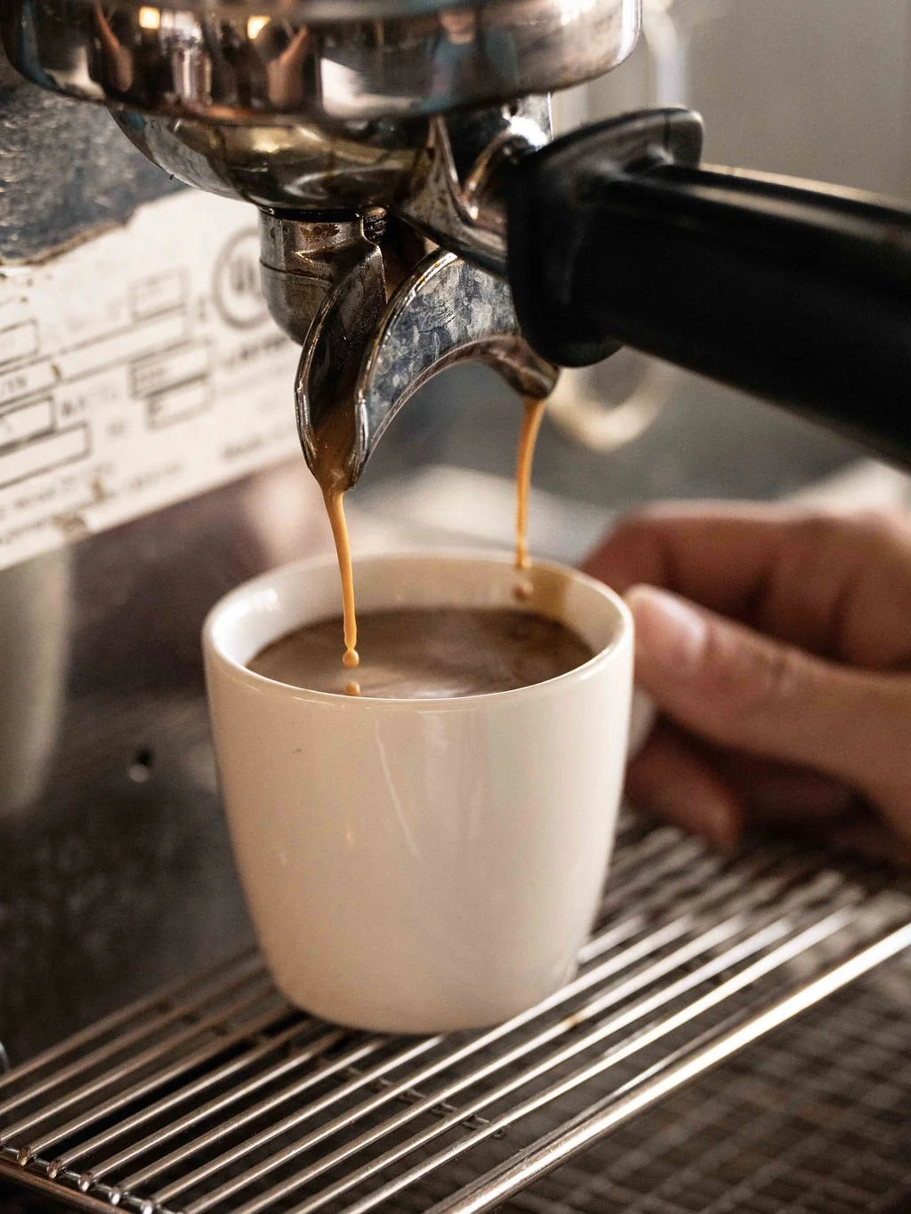 Close-up of a coffee machine pouring espresso into a white ceramic cup.