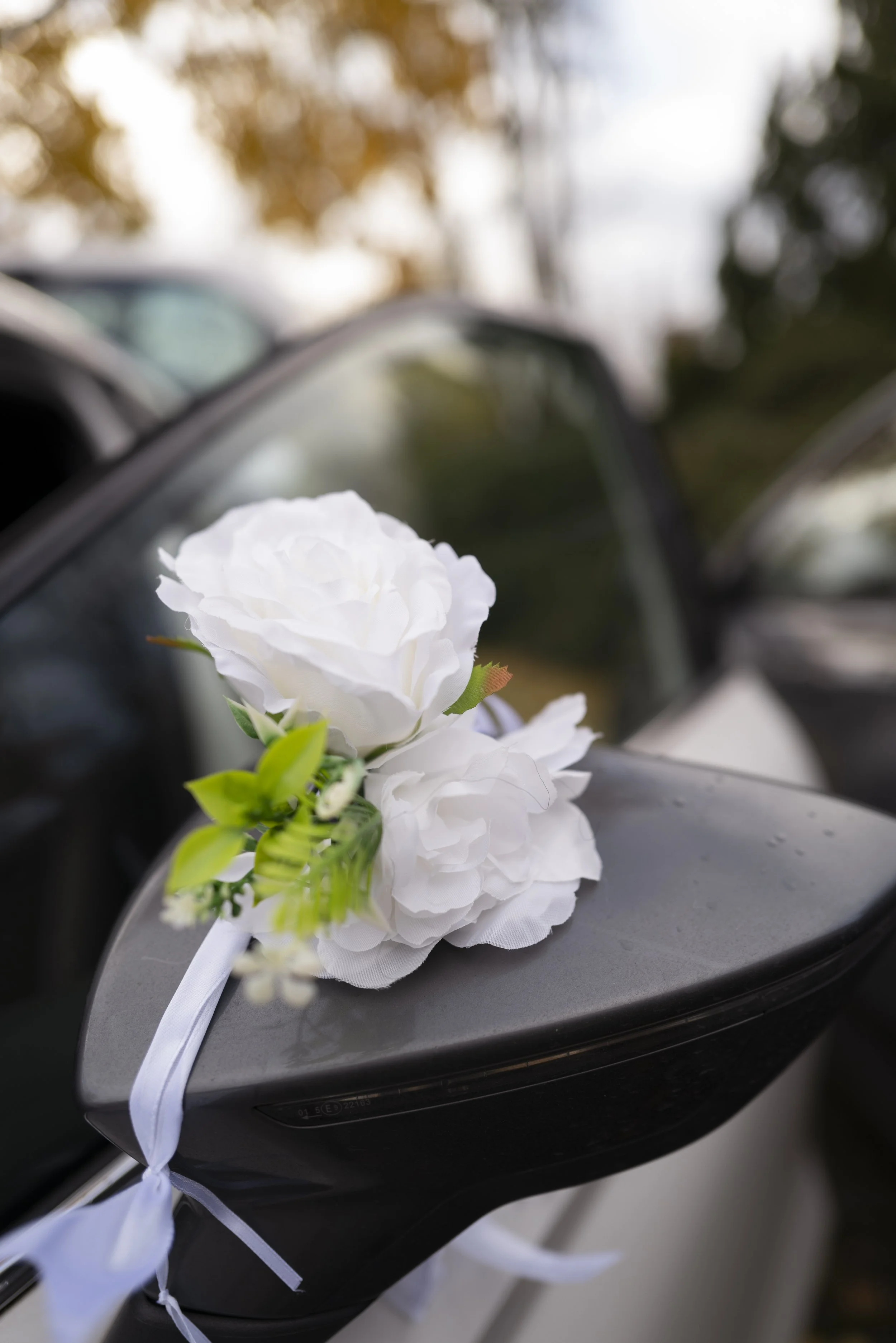Weiße Blumen und grüne Blätter, die an einem schwarzen Fahrzeug angebracht sind.