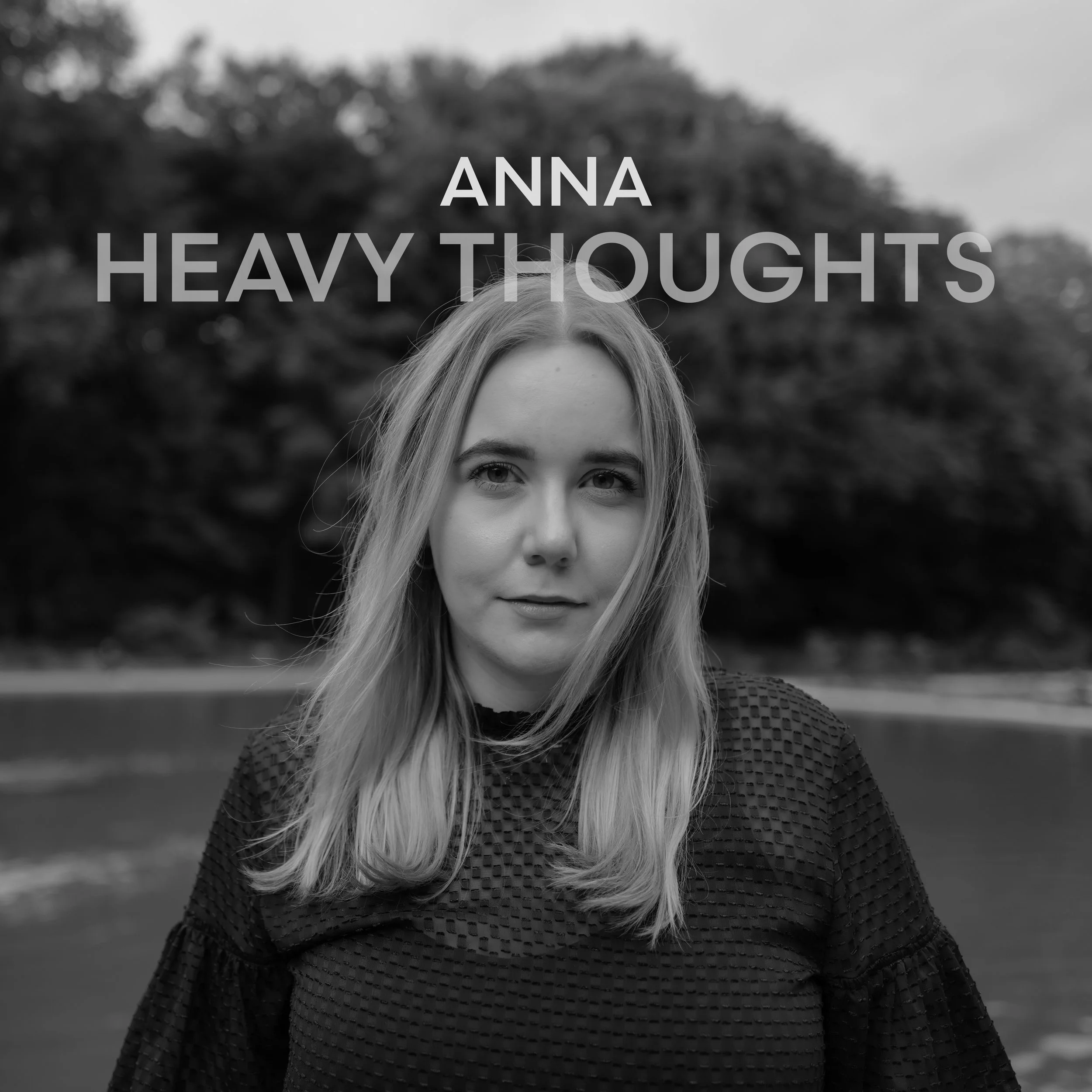 Schwarz-Weiß-Foto einer Frau im Vordergrund, im Hintergrund Wald. Schriftzug: ANNA HEAVY THOUGHTS.