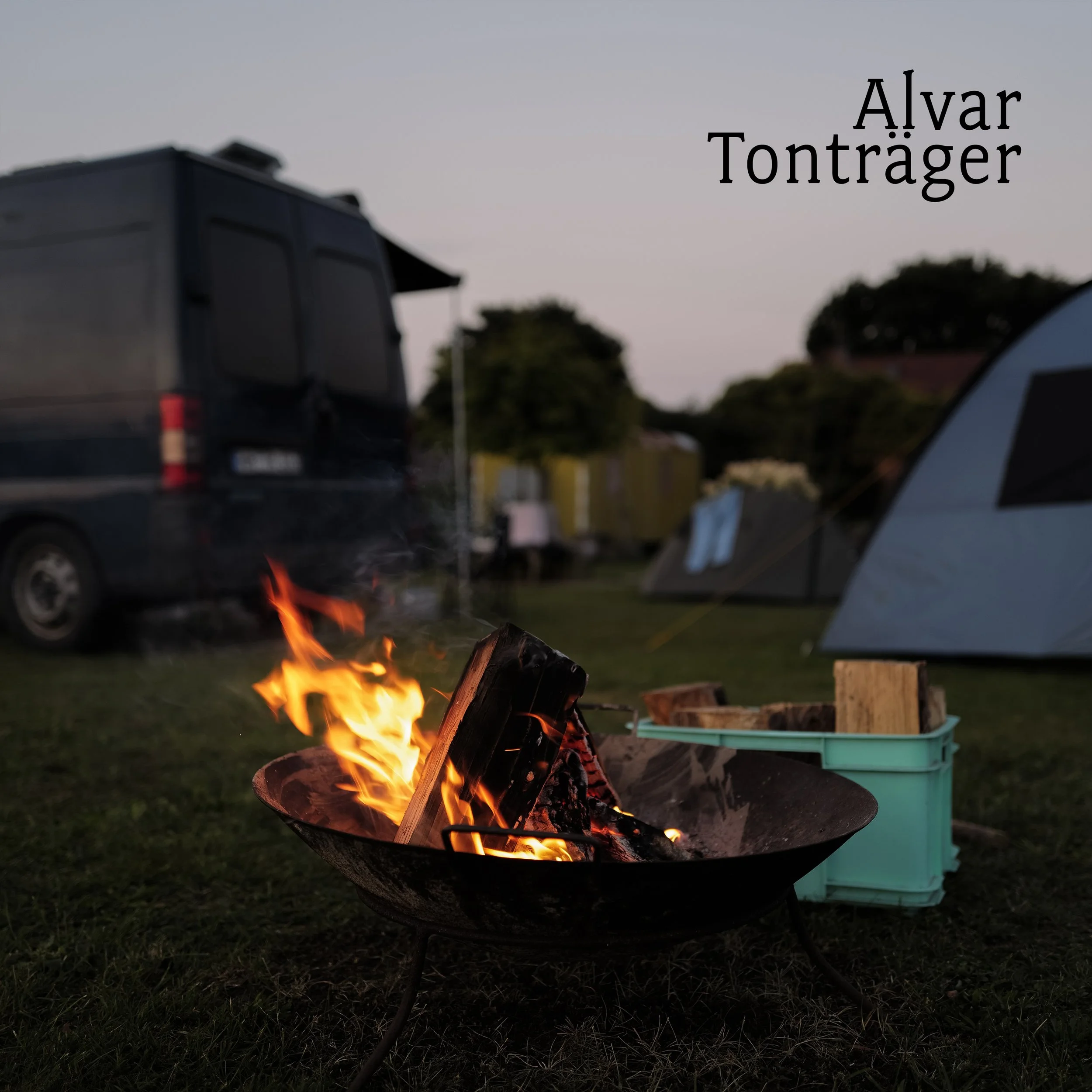 Lagerfeuer vor einem Campingplatz mit Van und Zelt im Hintergrund, während der Abenddämmerung. Text 'Alvar Tonträger' oben rechts.