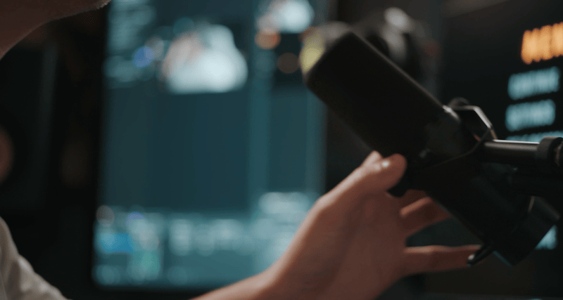 Person adjusting a camera or recording device in a dimly lit room.