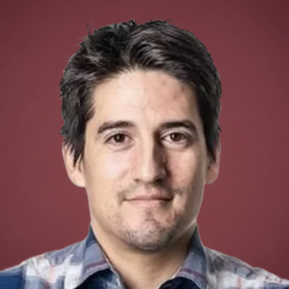 A person with short dark hair wearing a plaid shirt.