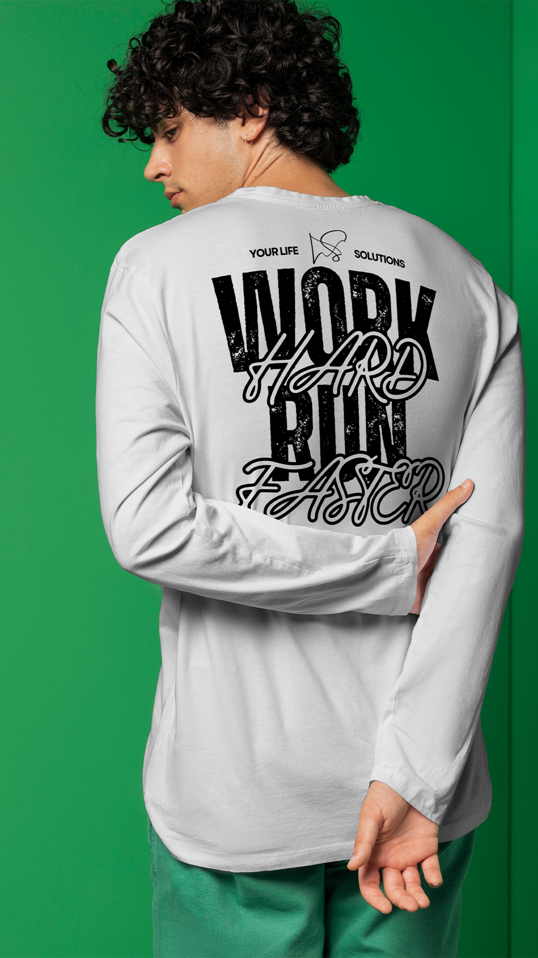 A young man with curly dark hair and a small earring is shown from the back, wearing a white long-sleeve shirt with bold black and cursive text and designs on the back, standing against a green background.