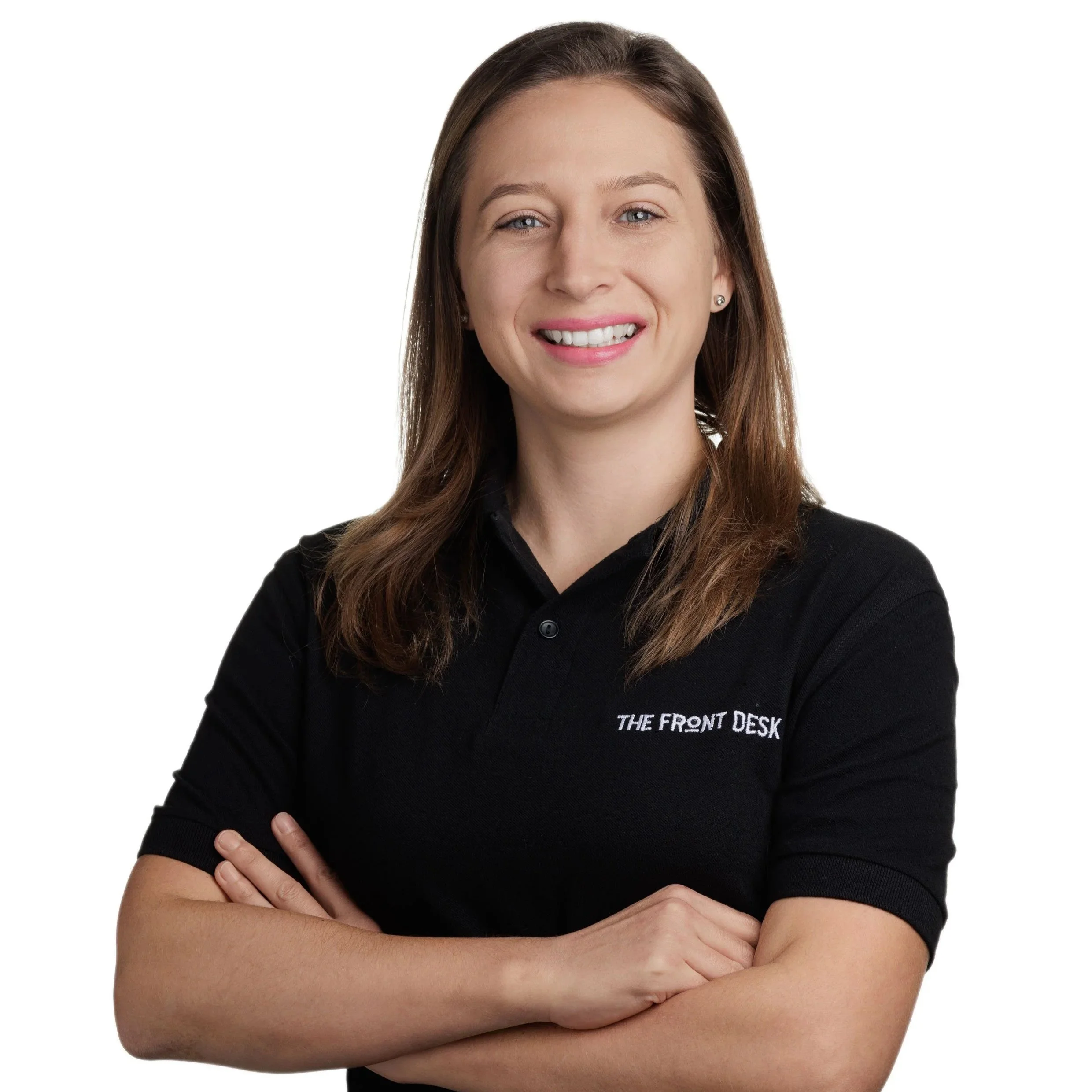 A smiling woman with shoulder-length brown hair, wearing a black polo shirt with the text 'THE FRONT DESK' embroidered on it, standing with arms crossed against a white background.