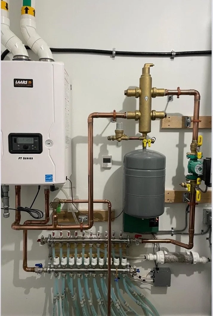 A plumbing and heating system with pipes, a water heater, and control components attached to a white wall.