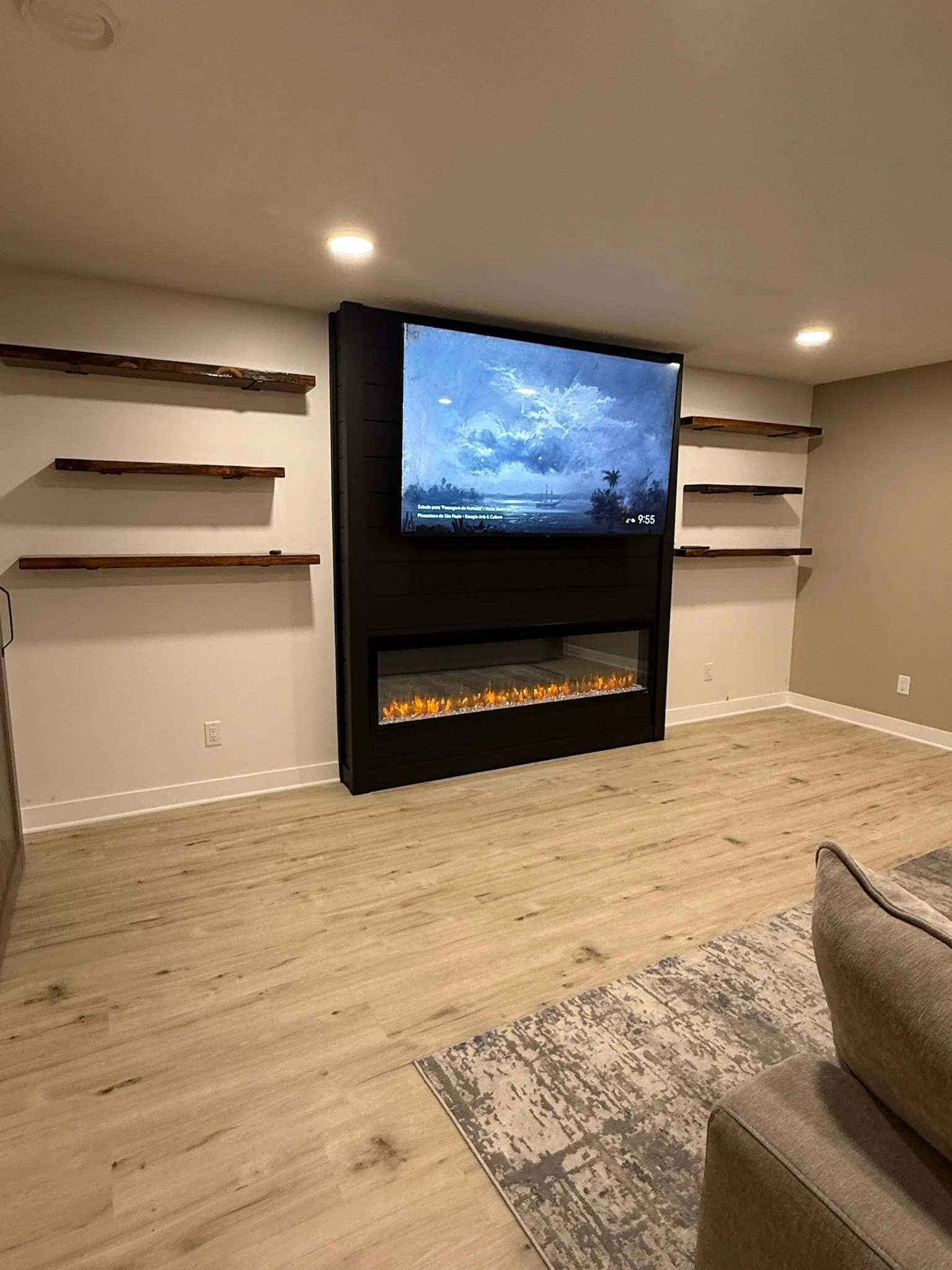 Cambridge MN basement remodel with electric fireplace, vinyl plank flooring and floating shelves