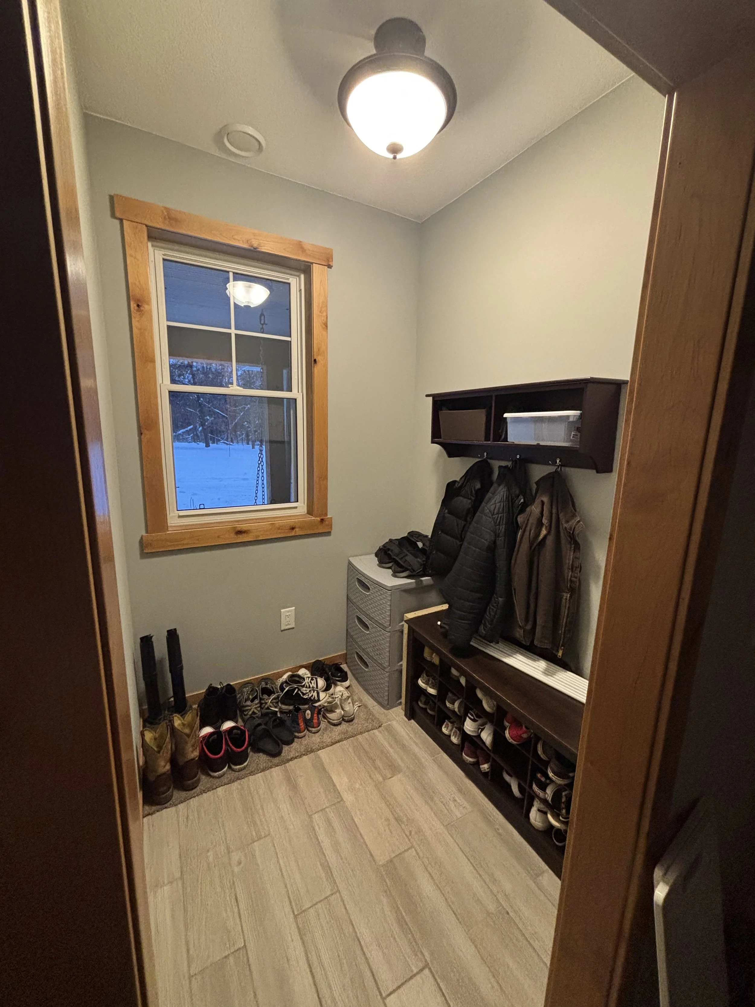 Before photo of entryway with hanging coats and open shoe rack – Minnesota mudroom remodel 2025