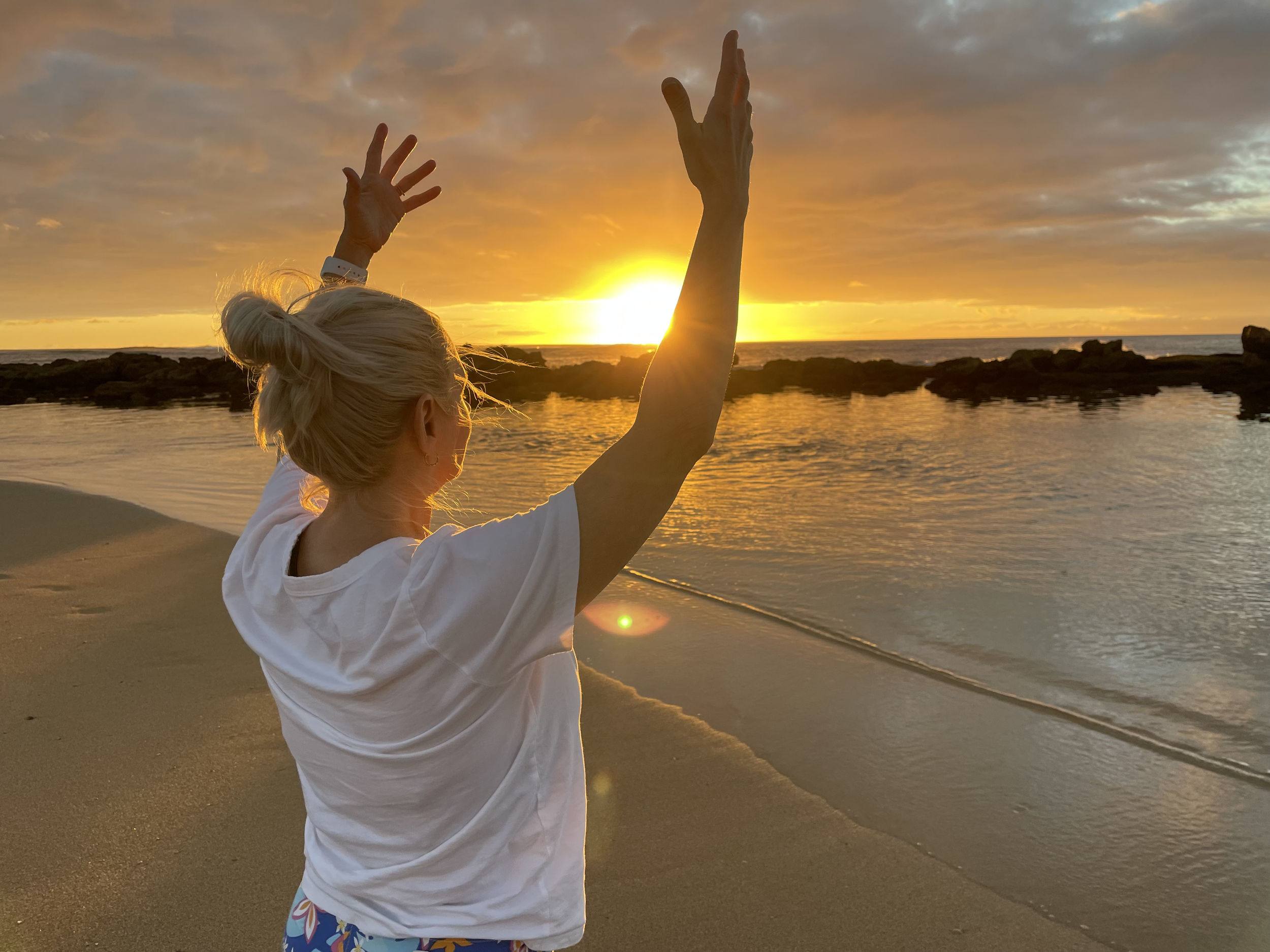 woman practicing qi gong on the beach at sunset