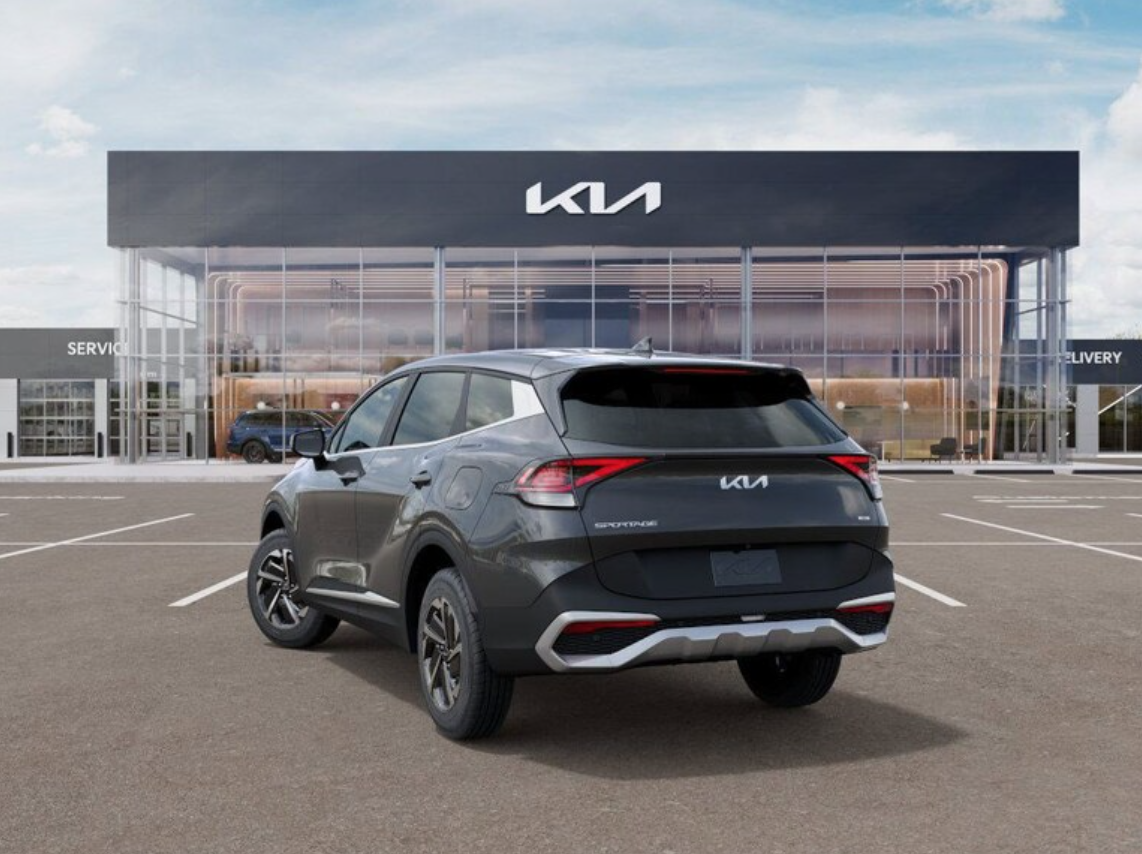 Kia Sportage SUV parked in front of a Kia dealership with glass facade.