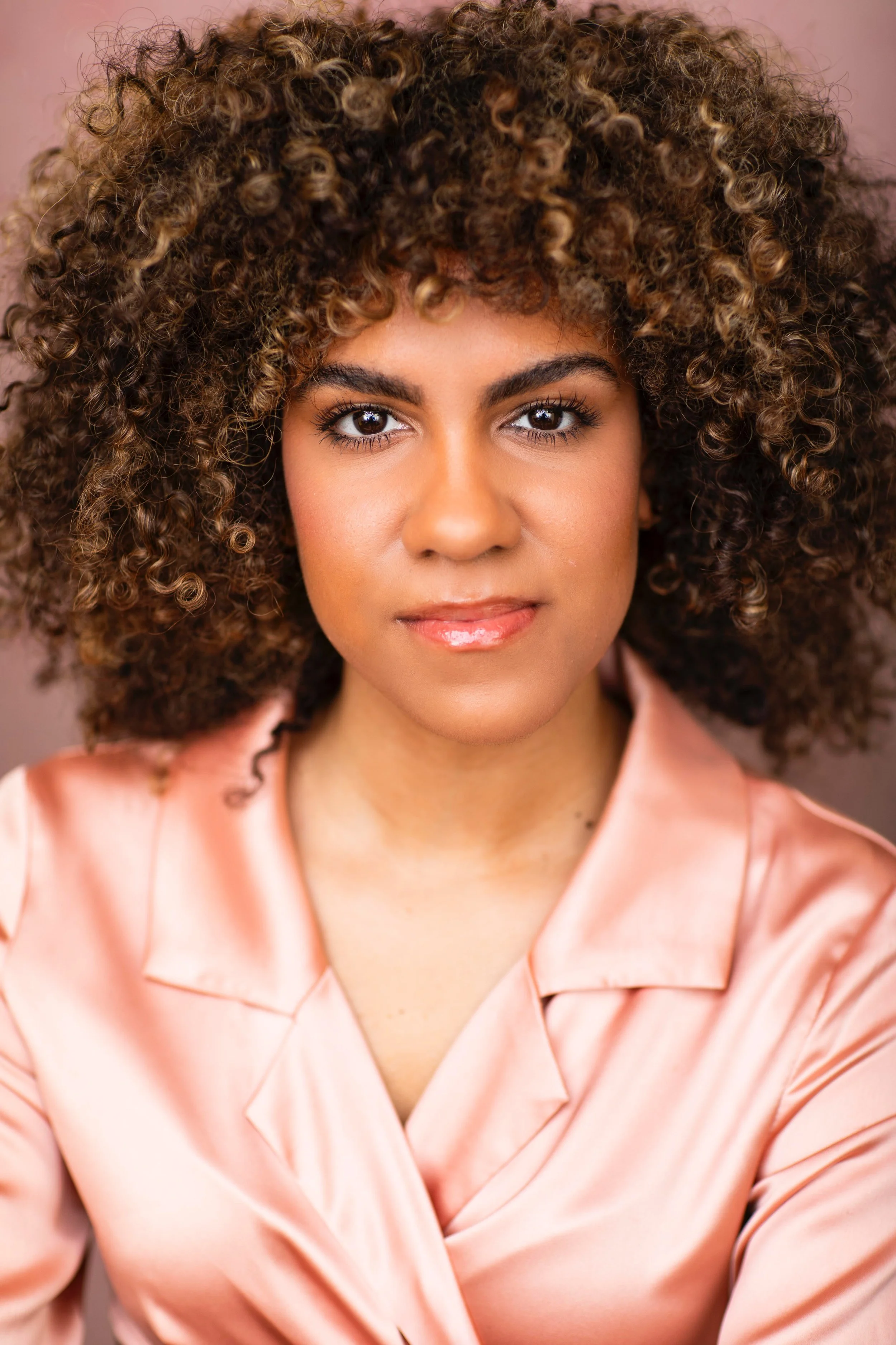 Jolimar looking at the camera wearing a pink, satin collared top