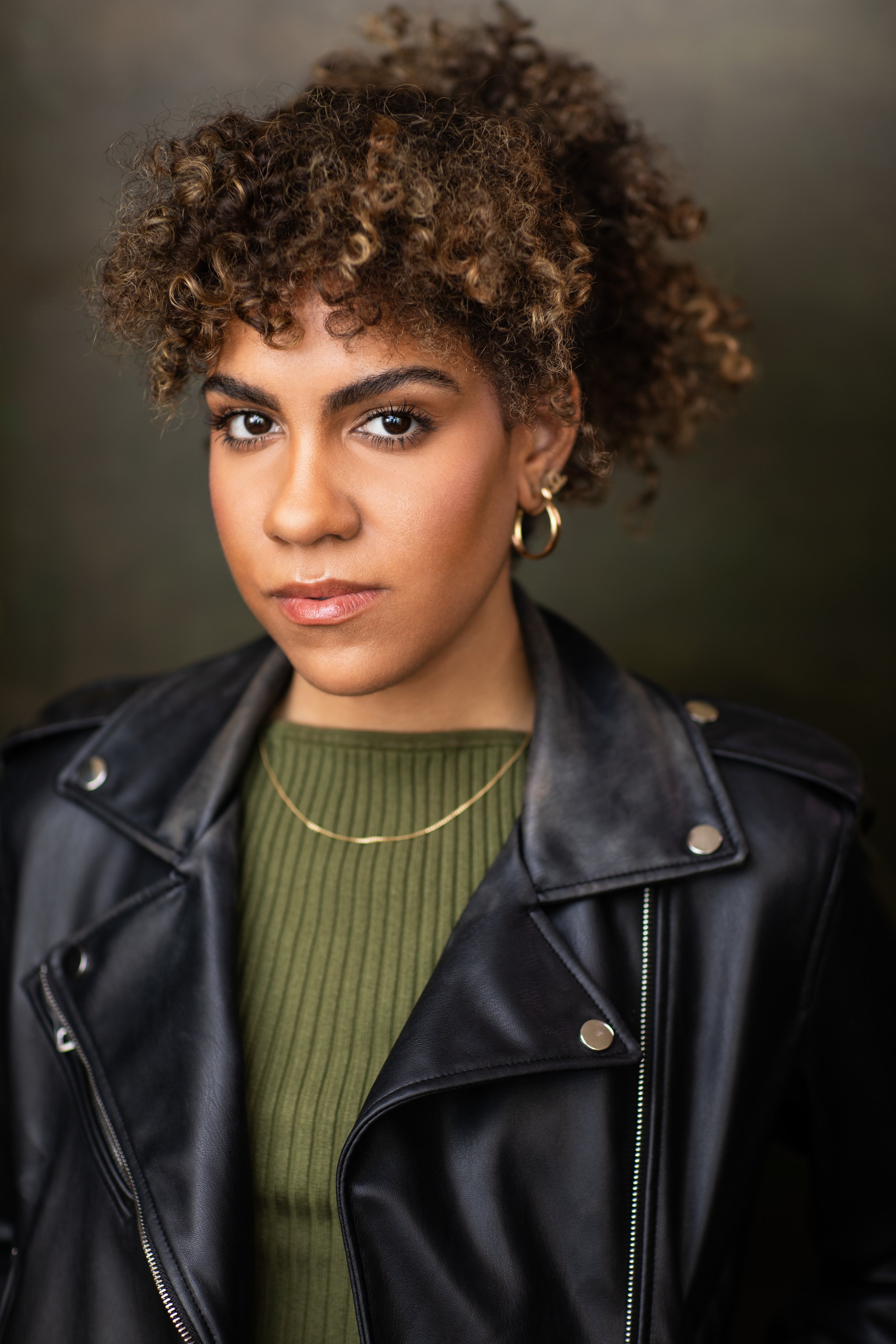 Jolimar looking at the camera, wearing a green top with black leather jacket