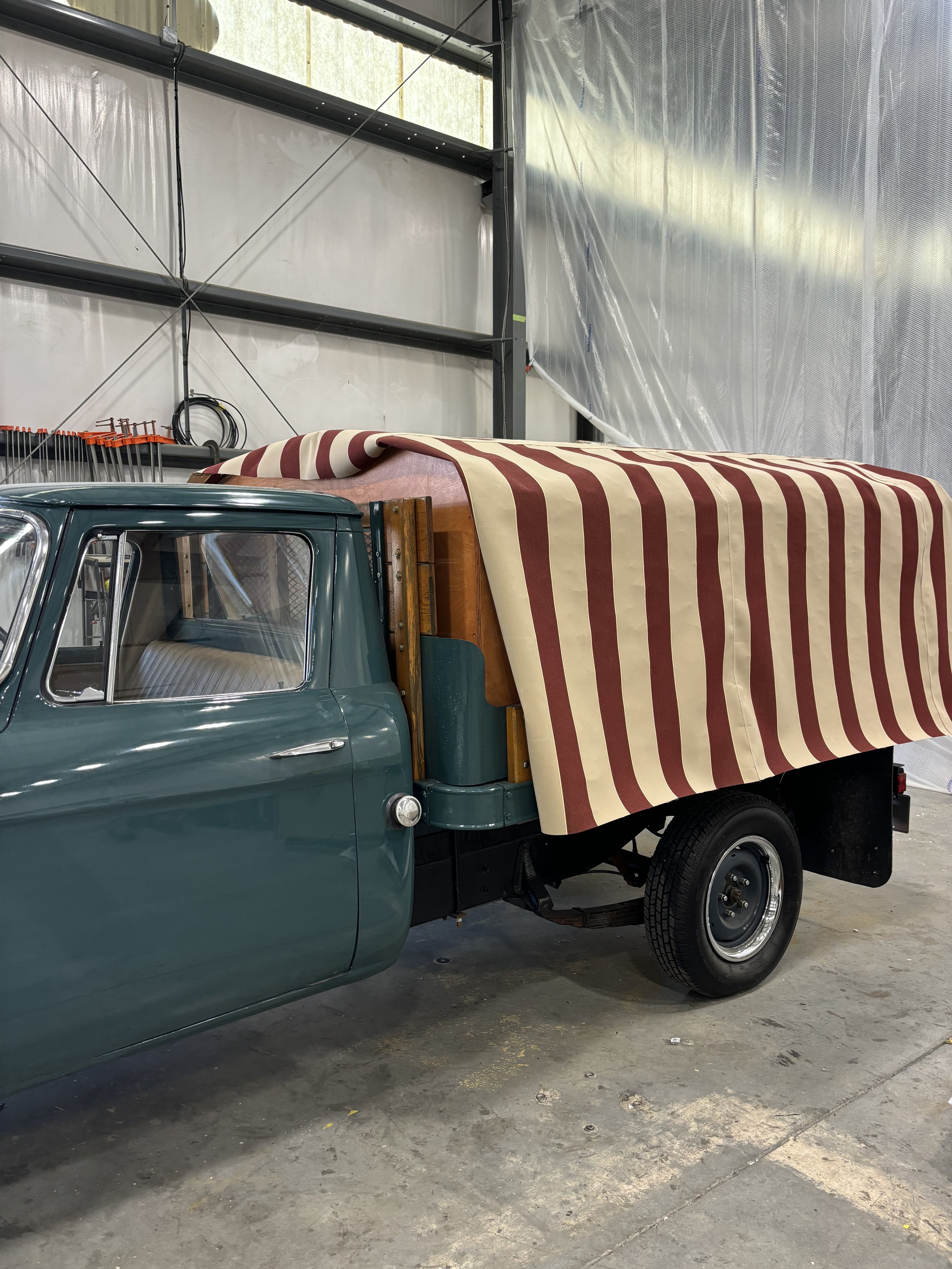 Vintage truck with a red and cream striped canopy in a garage.