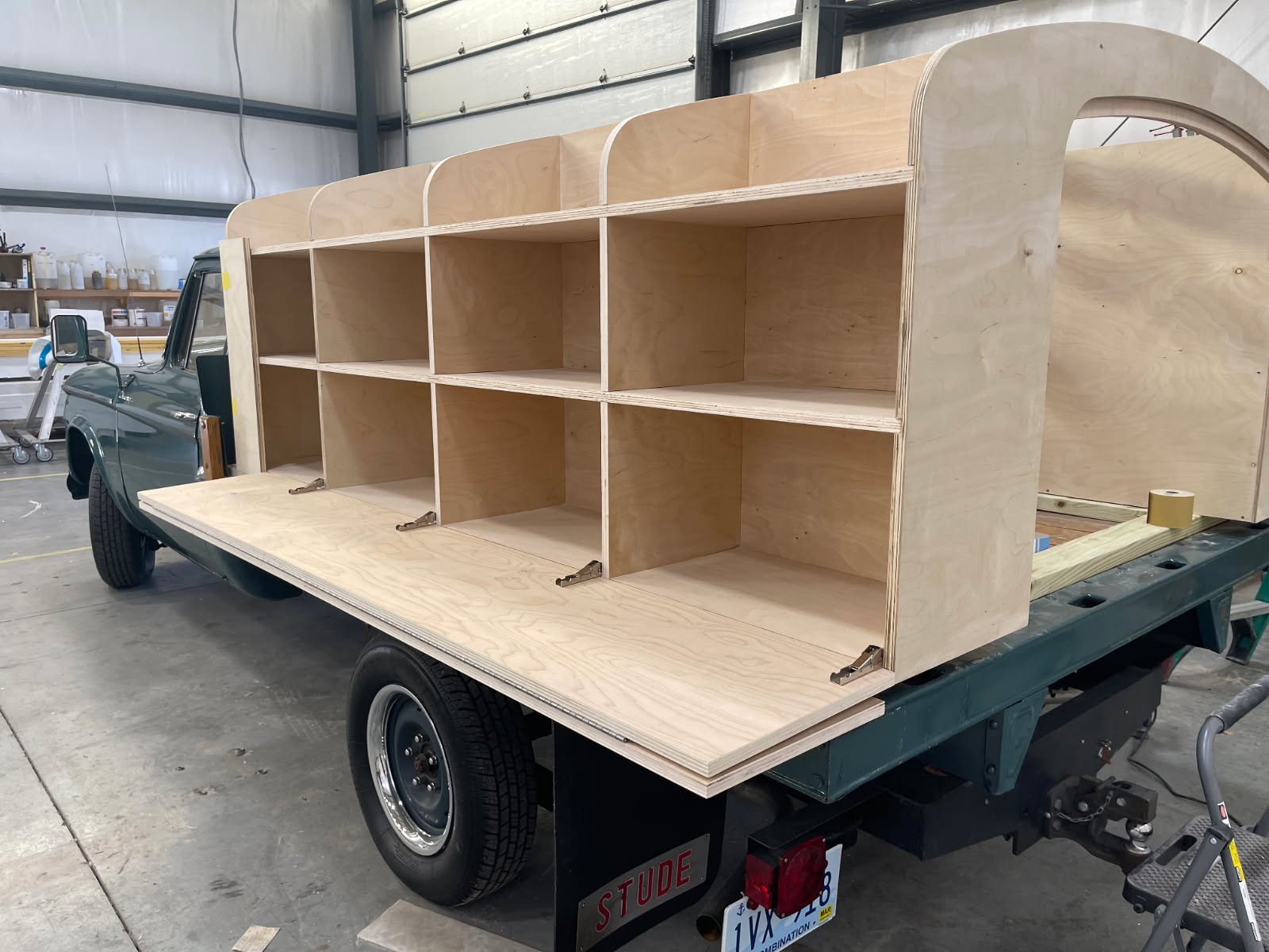 Wooden shelving unit on the back of a flatbed truck in a workshop setting