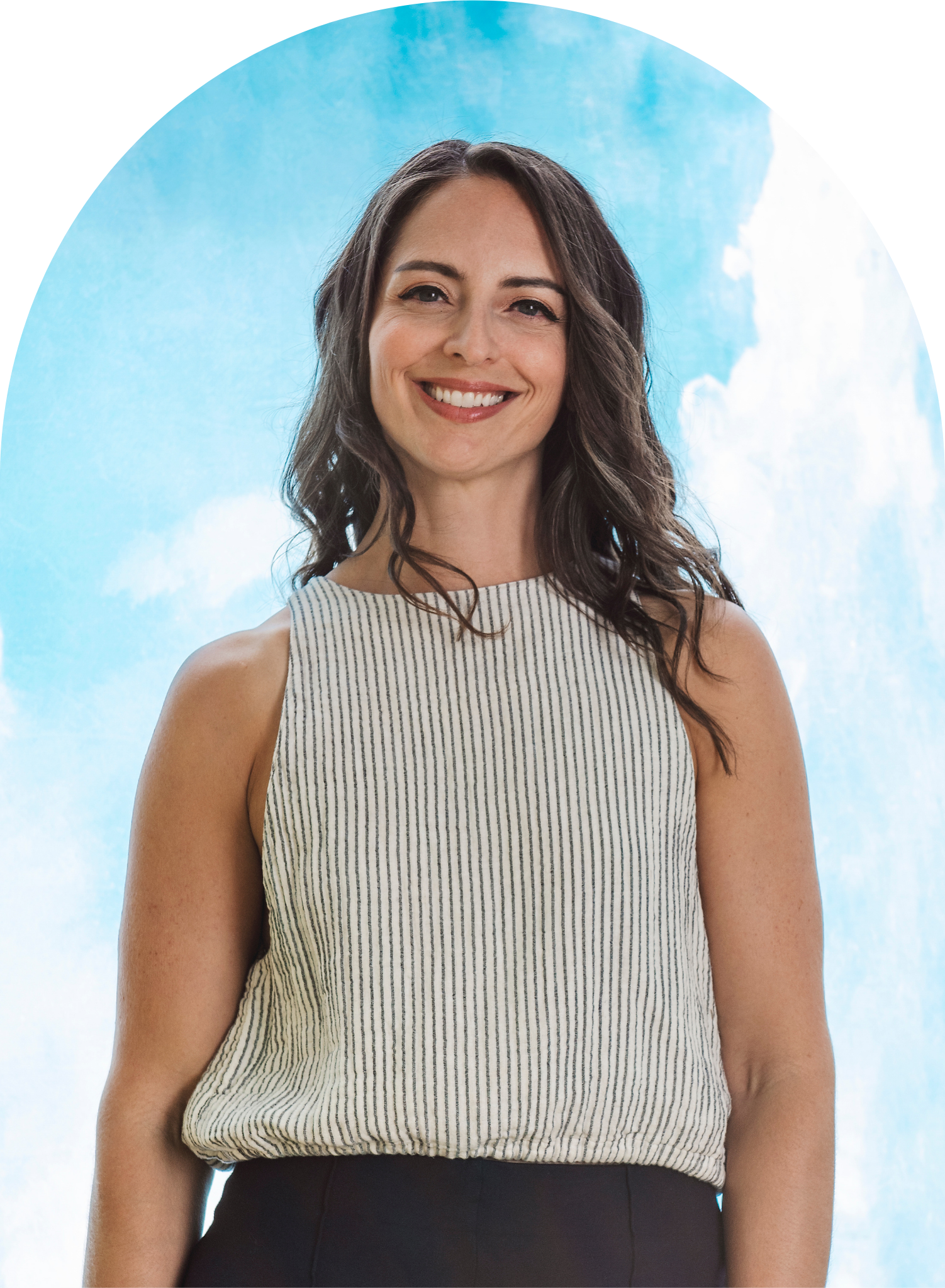 Smiling woman with long dark hair wearing a striped sleeveless top against a bright blue sky